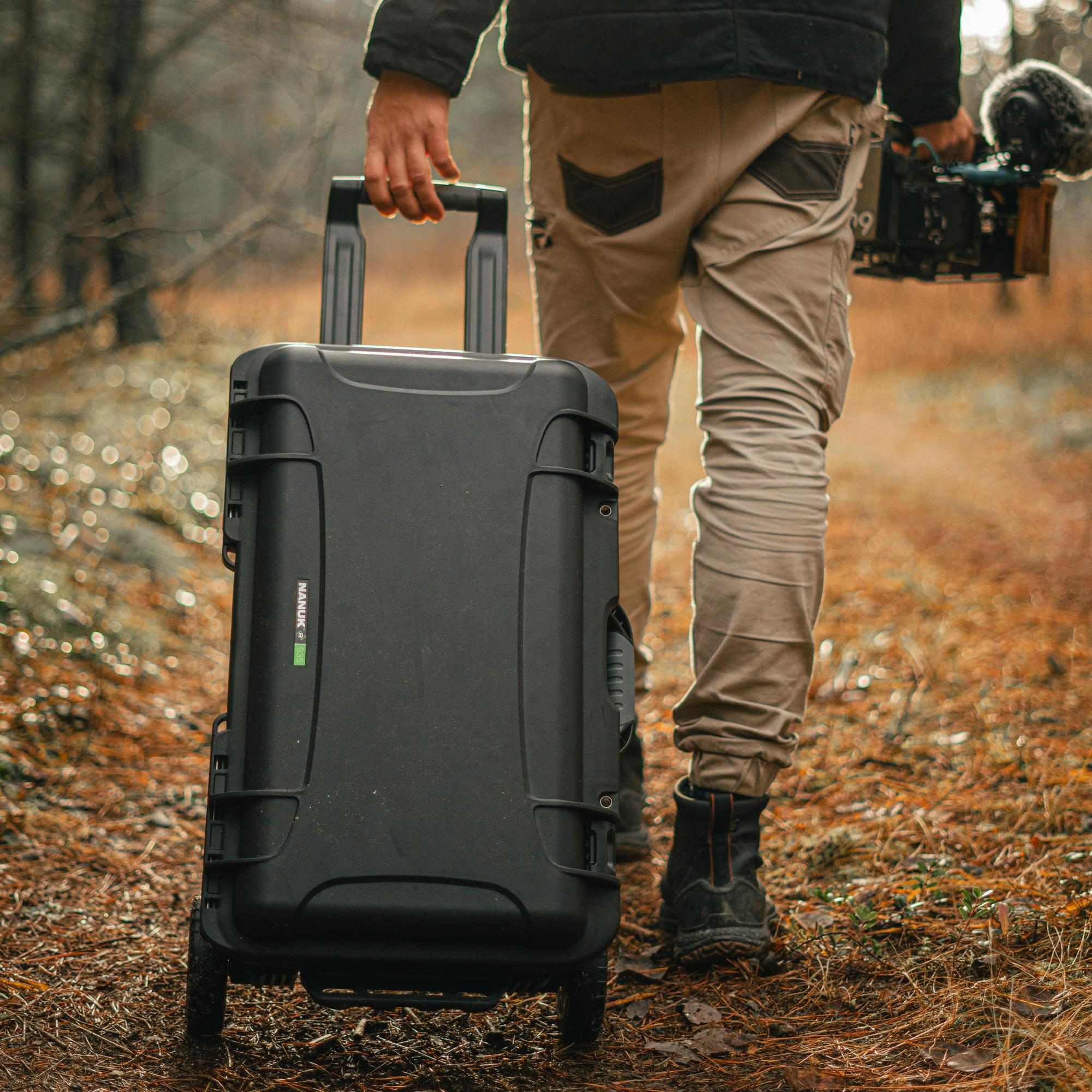 Person walking through a forest with a large black suitcase. Person walking through a forest with a large black suitcase.