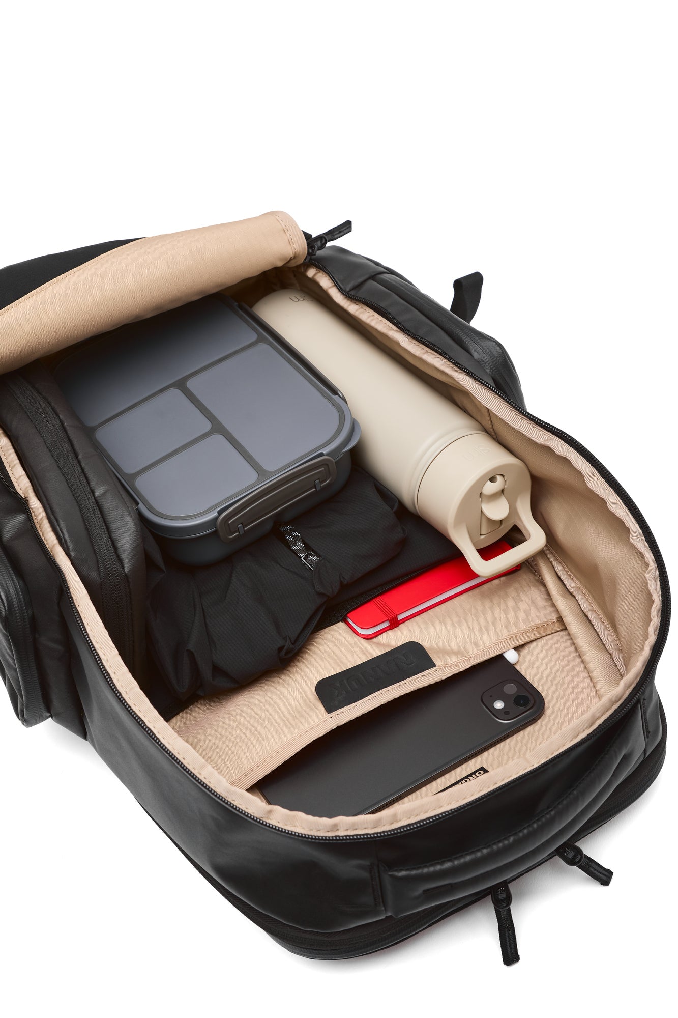Open black backpack with beige interior showing various items including a water bottle and a container. Open black backpack with beige interior showing various items including a water bottle and a container.