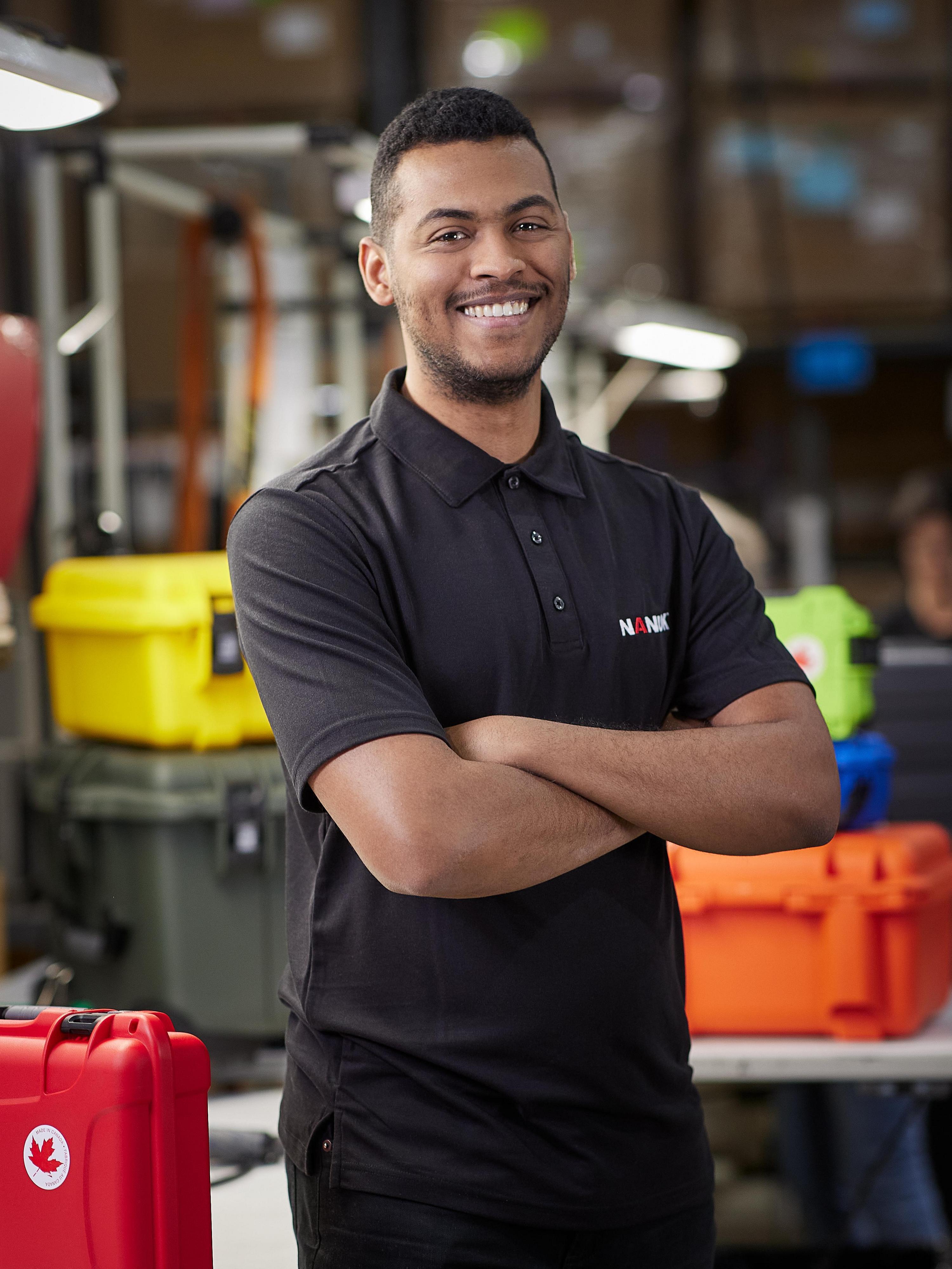 Man in a black shirt with a logo standing in a warehouse setting