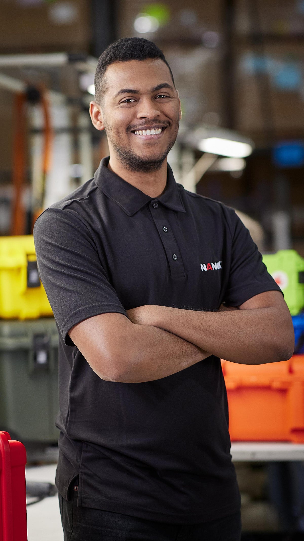 Man in a black shirt with a logo standing in a warehouse setting