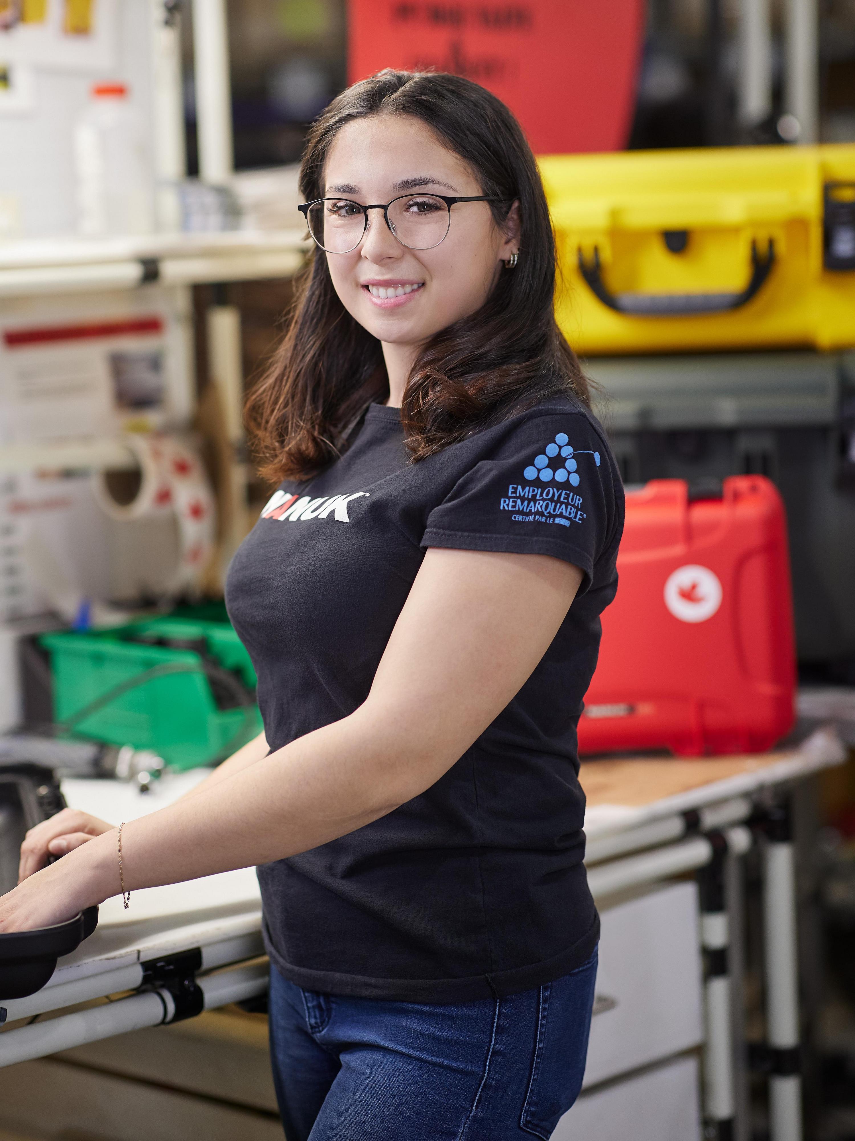 Woman wearing a black t-shirt with a logo in a workshop setting