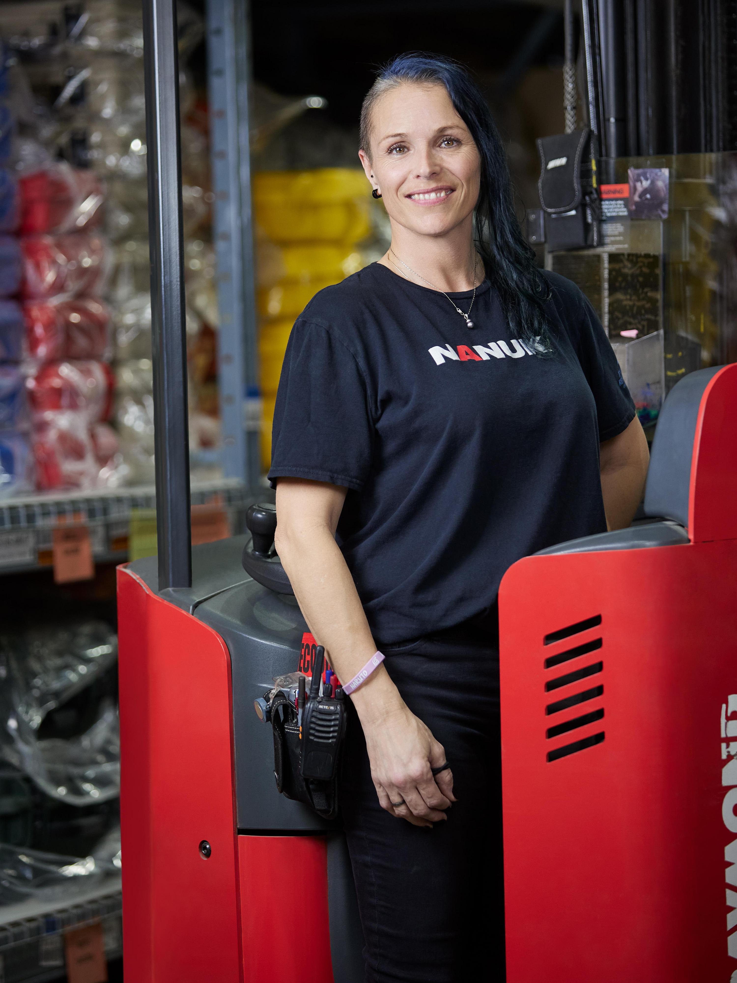 Person wearing a black shirt with 'Ranuck' logo standing next to a red forklift in an industrial setting.