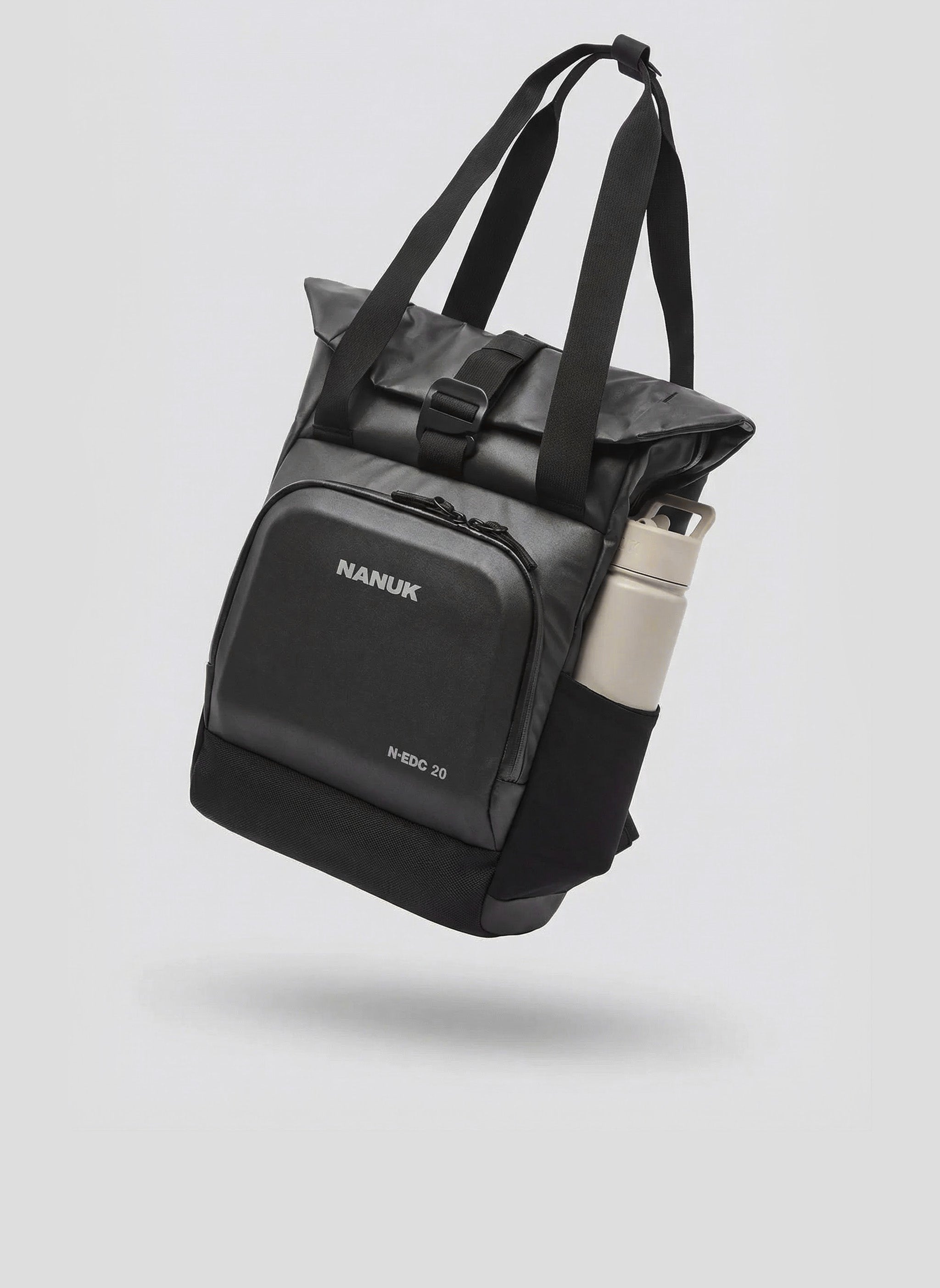 A black Nanuk N-EDC 20 bag with a roll-top buckle closure and a water bottle in its side pocket is presented floating against a light gray background, highlighting its functionality among nanuk bags and cases.