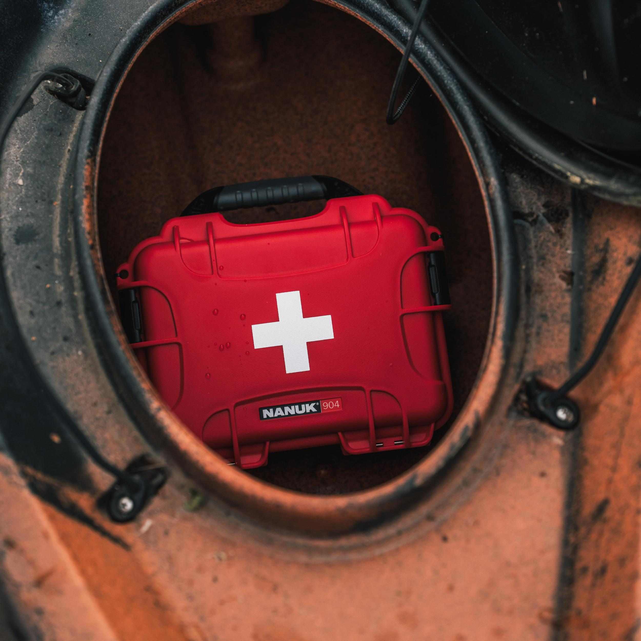 Red Nanuk hard-shell case with a white cross logo inside a circular opening.