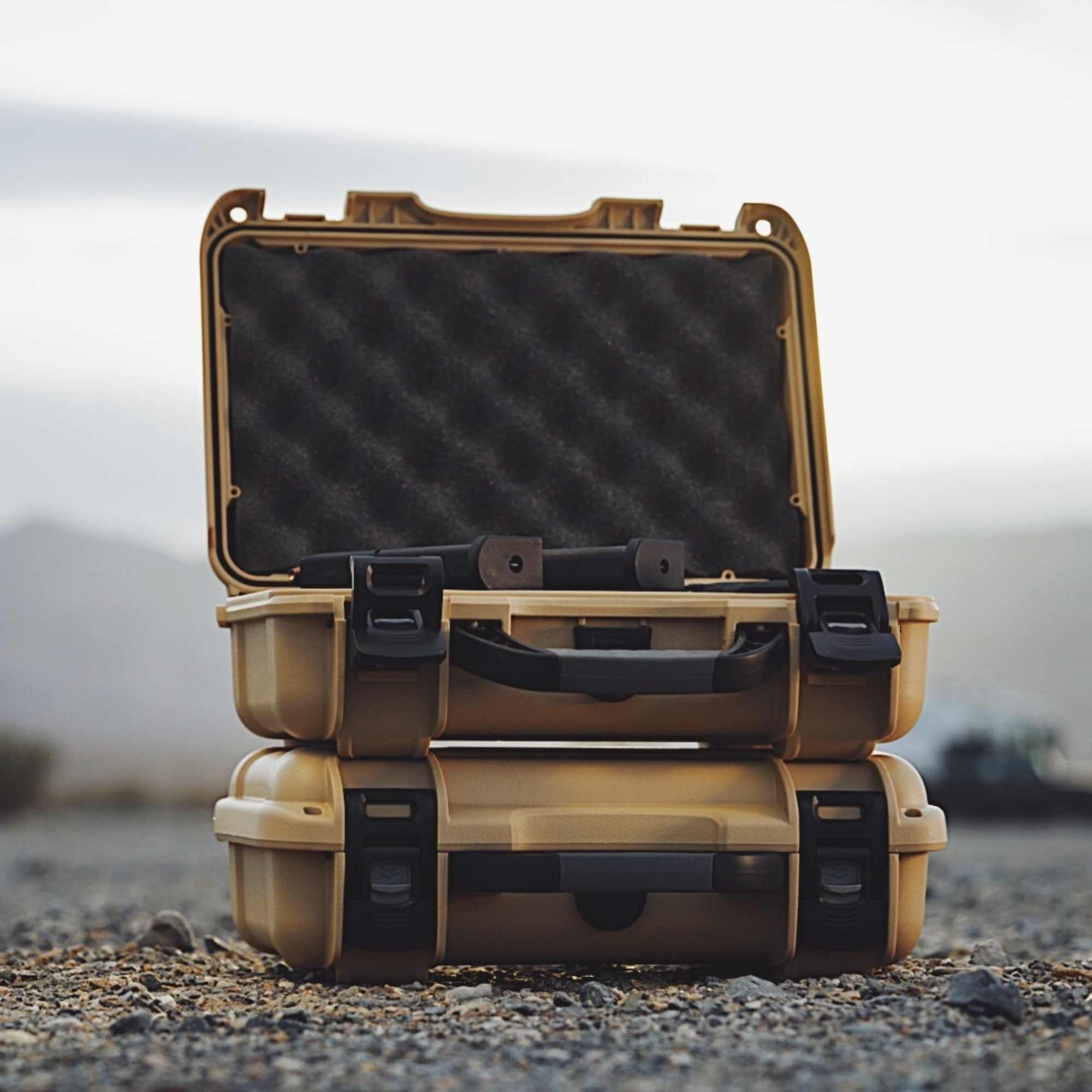 Stack of open beige hard-shell cases on a gravel surface with a blurred natural background Stack of open beige hard-shell cases on a gravel surface with a blurred natural background
