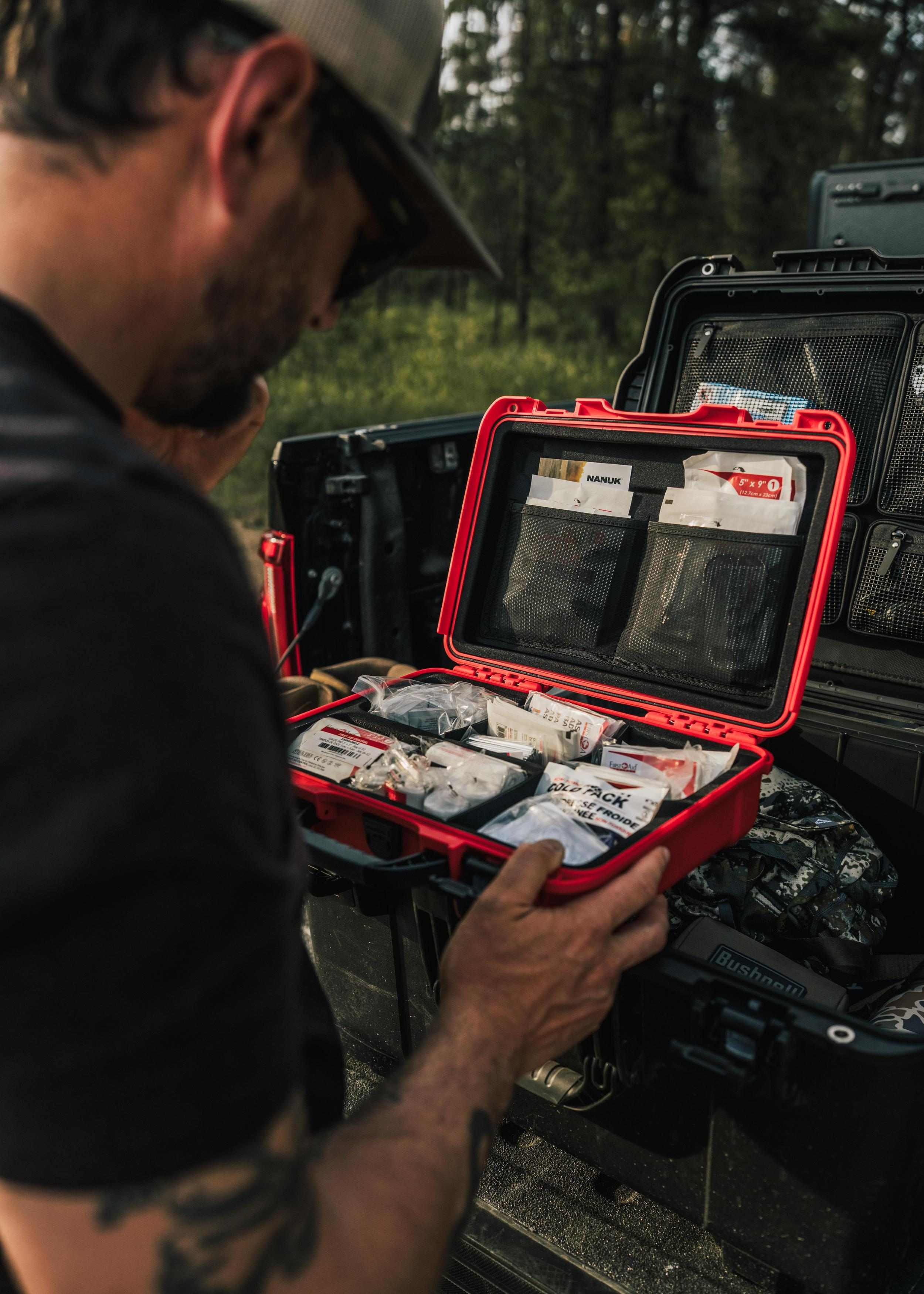 Person organizing items in a red and black case outdoors Person organizing items in a red and black case outdoors