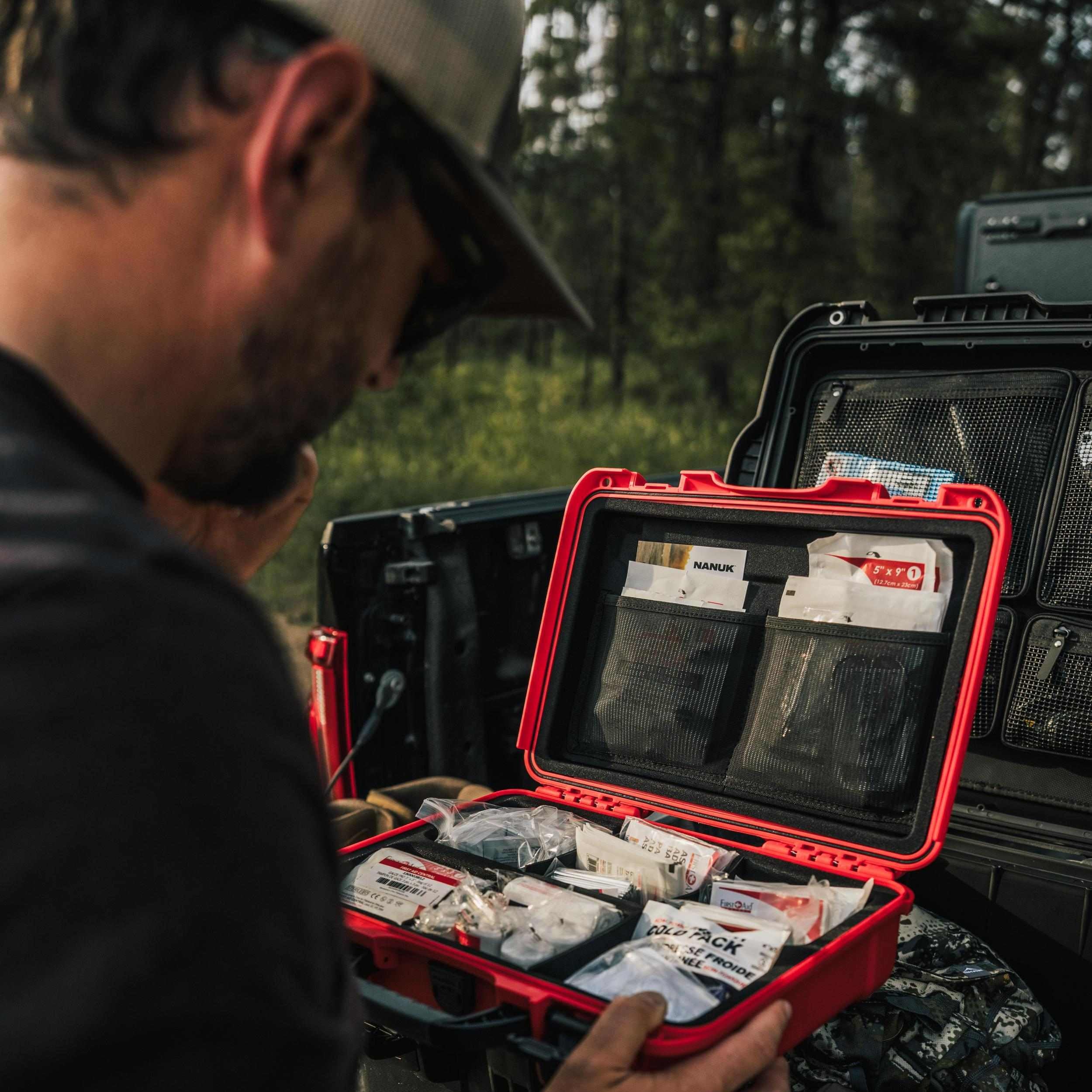 Person organizing items in a red and black case outdoors