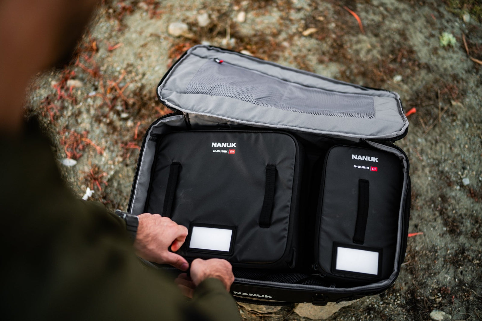 Person holding an open black Nanuk suitcase with visible branding.