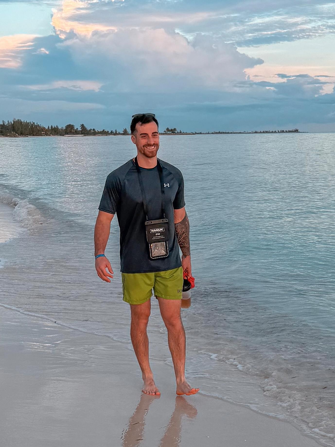 Man standing on a beach with a scenic sky and water background