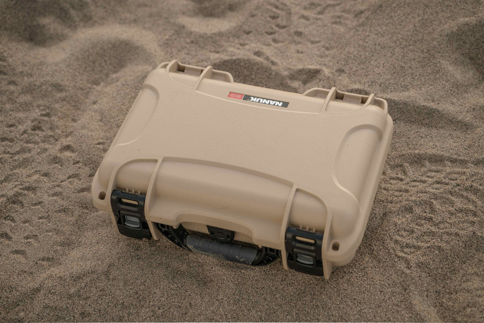 Protective NANUK 909 Hard Case in a sandy environment, showcasing rugged outdoor reliability.