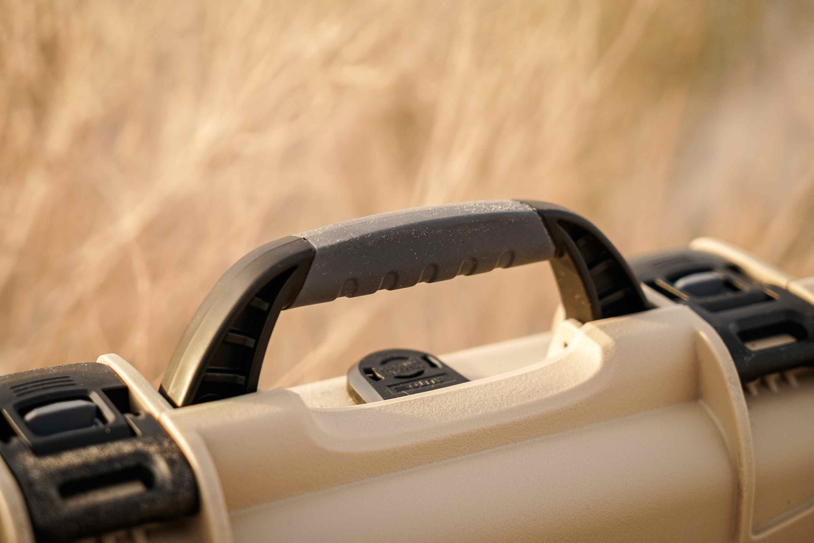 NANUK 909 Hard Case in tan, designed for outdoor adventures, sitting securely in desert sand.