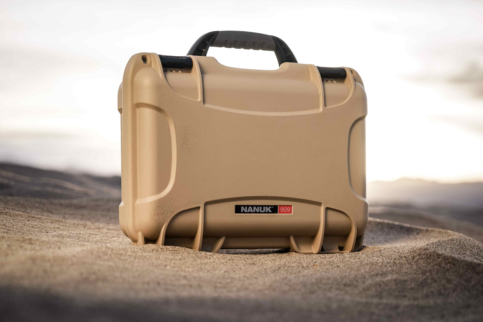Rugged NANUK 909 Hard Case in tan, built to endure extreme conditions, showcased on a desert terrain.