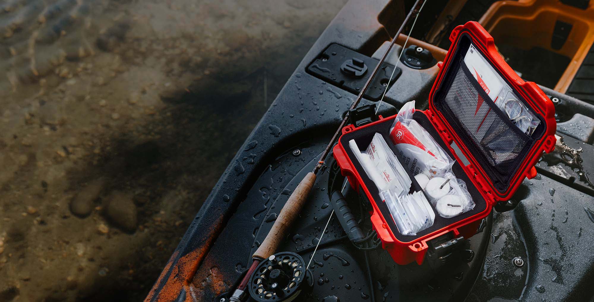 Close-up of someone arranging medical supplies inside a red NANUK First Aid Case in a wooded area.