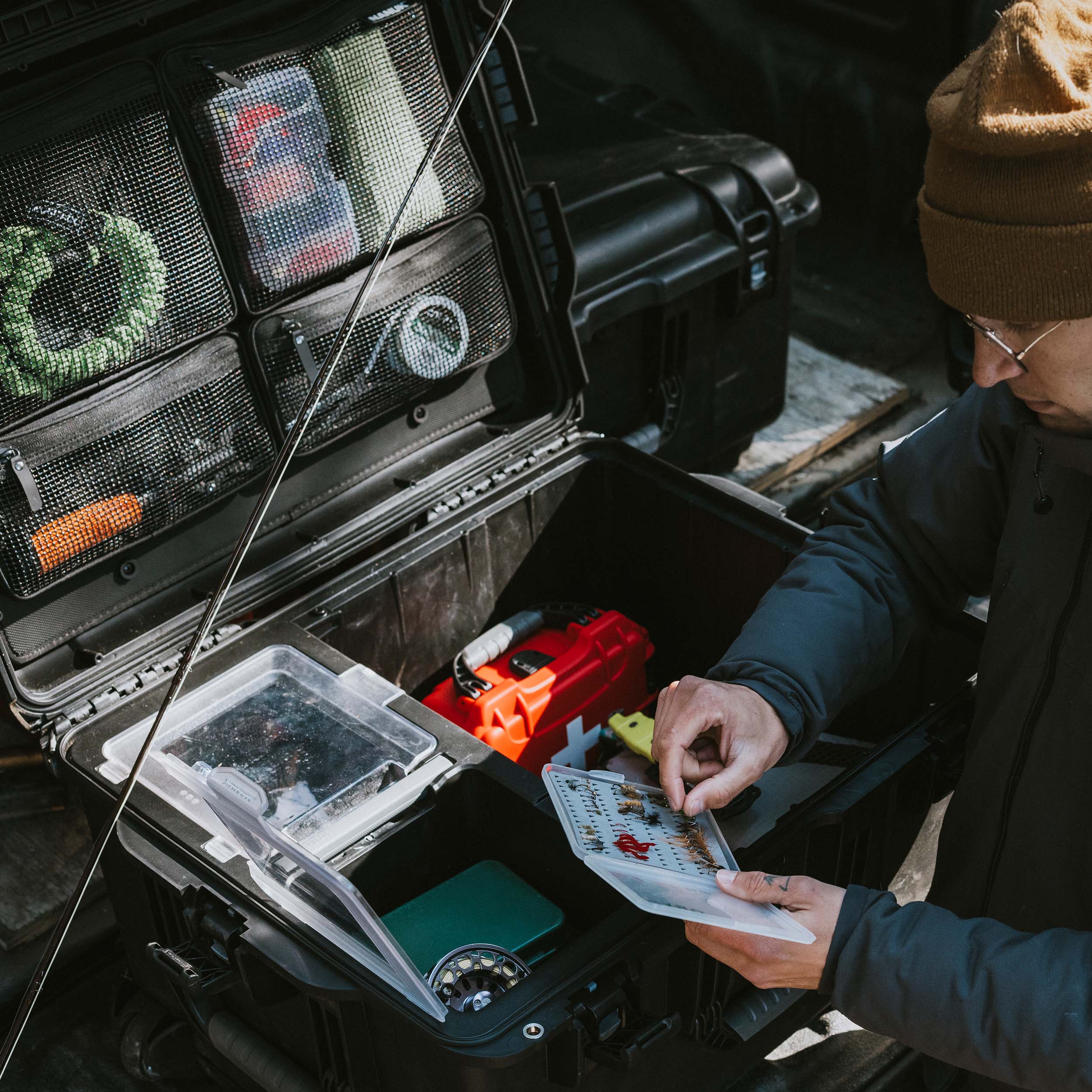 Overhead view of an open black NANUK Trail 80 case on the ground, displaying photography equipment and accessories neatly arranged in its modular trays.