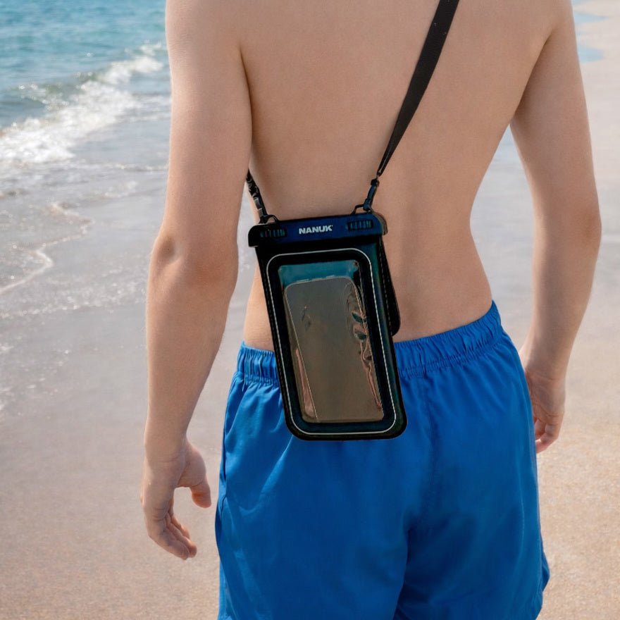 Person wearing a blue swimsuit with a phone case on a beach