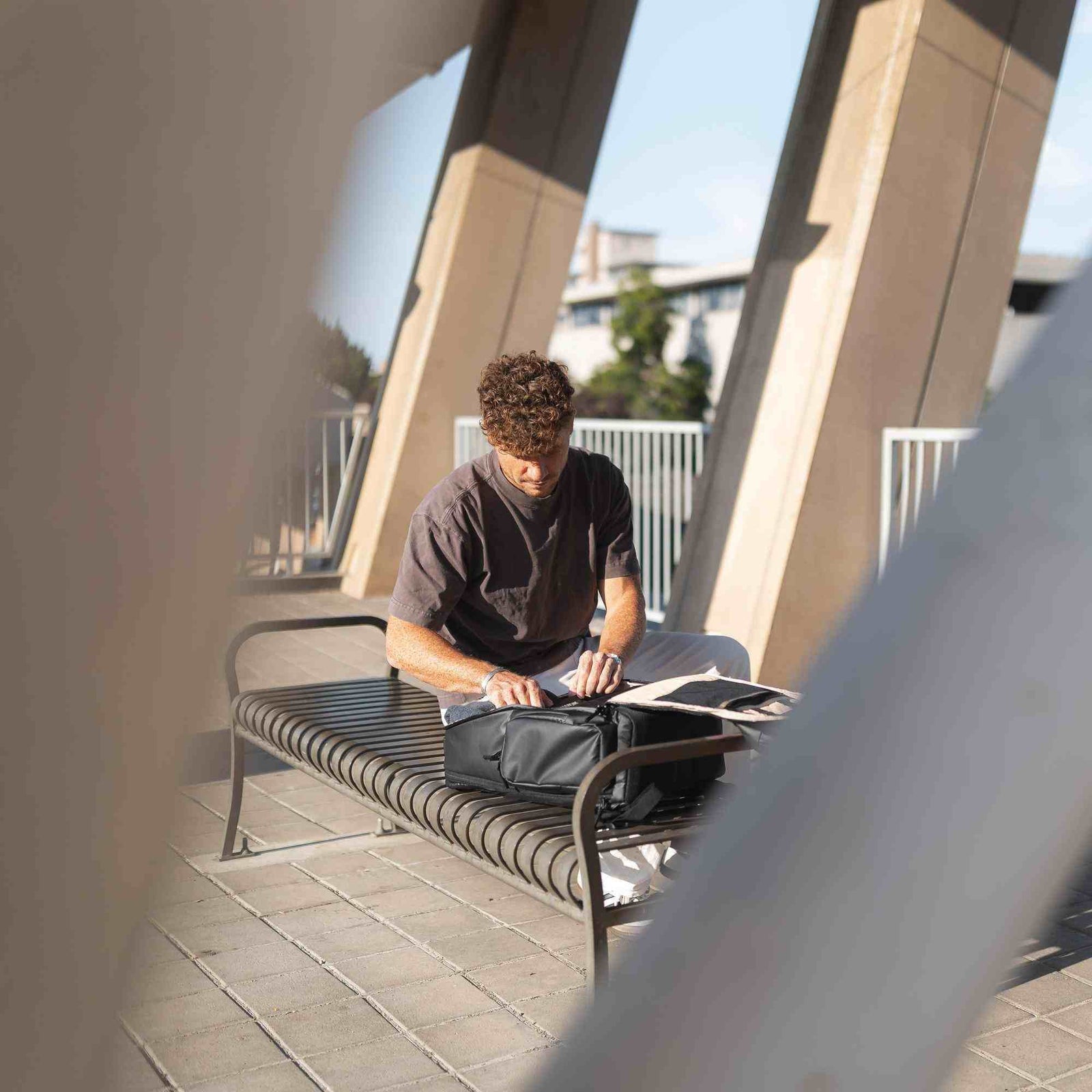 Man sitting on a bench outdoors using a laptop