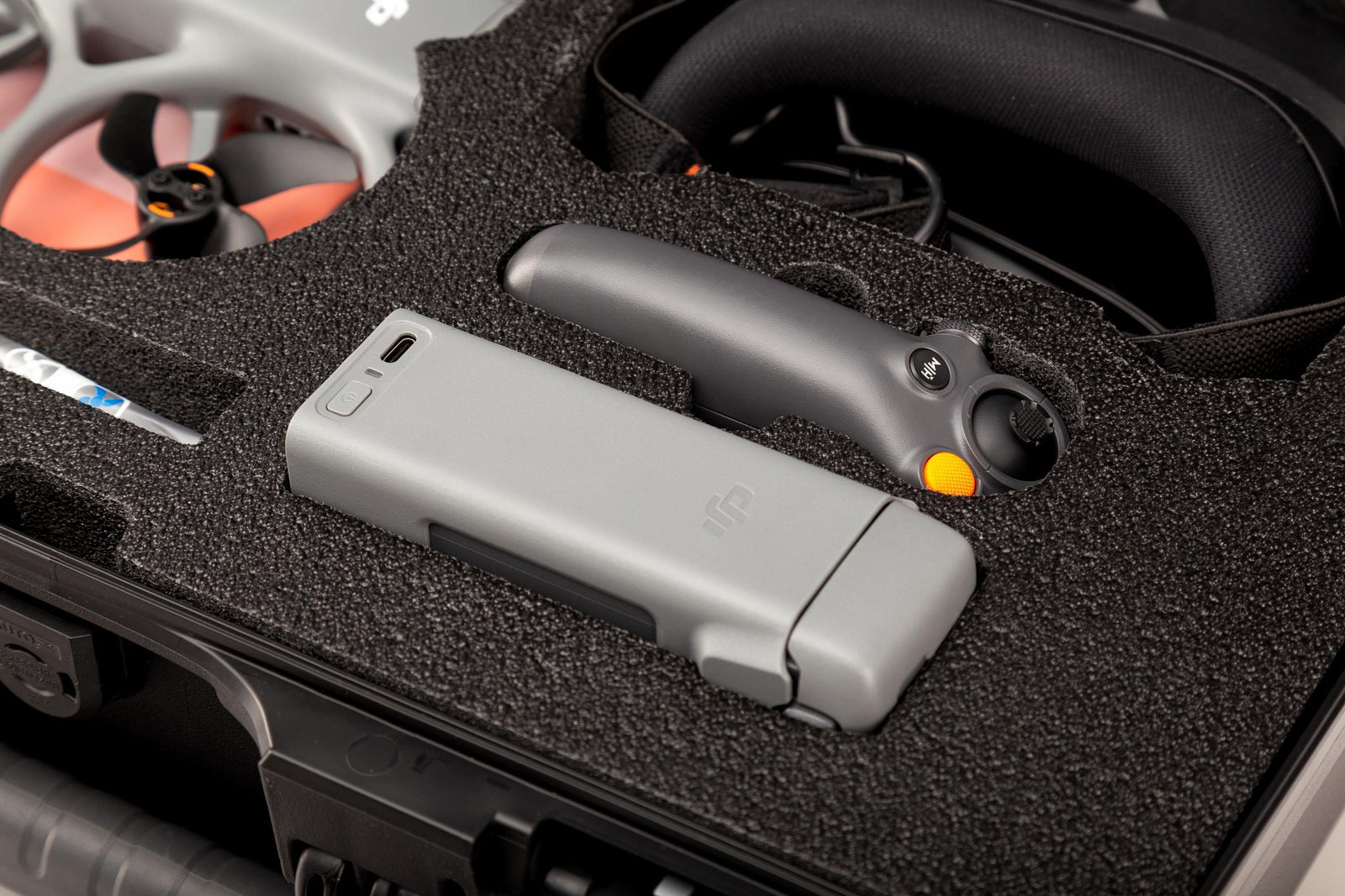Gray electronic device with a yellow button on a black foam-lined surface