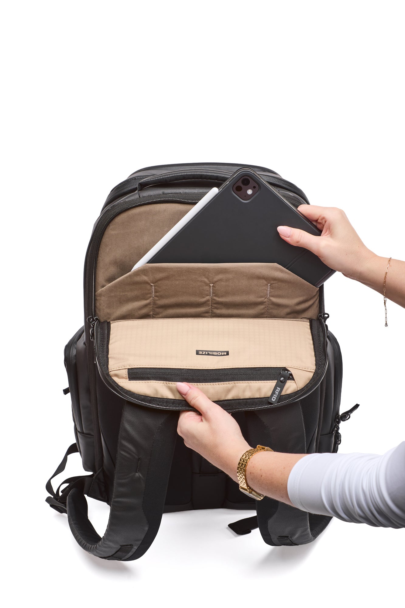 Person opening a black backpack to reveal a beige interior with a tablet inside.