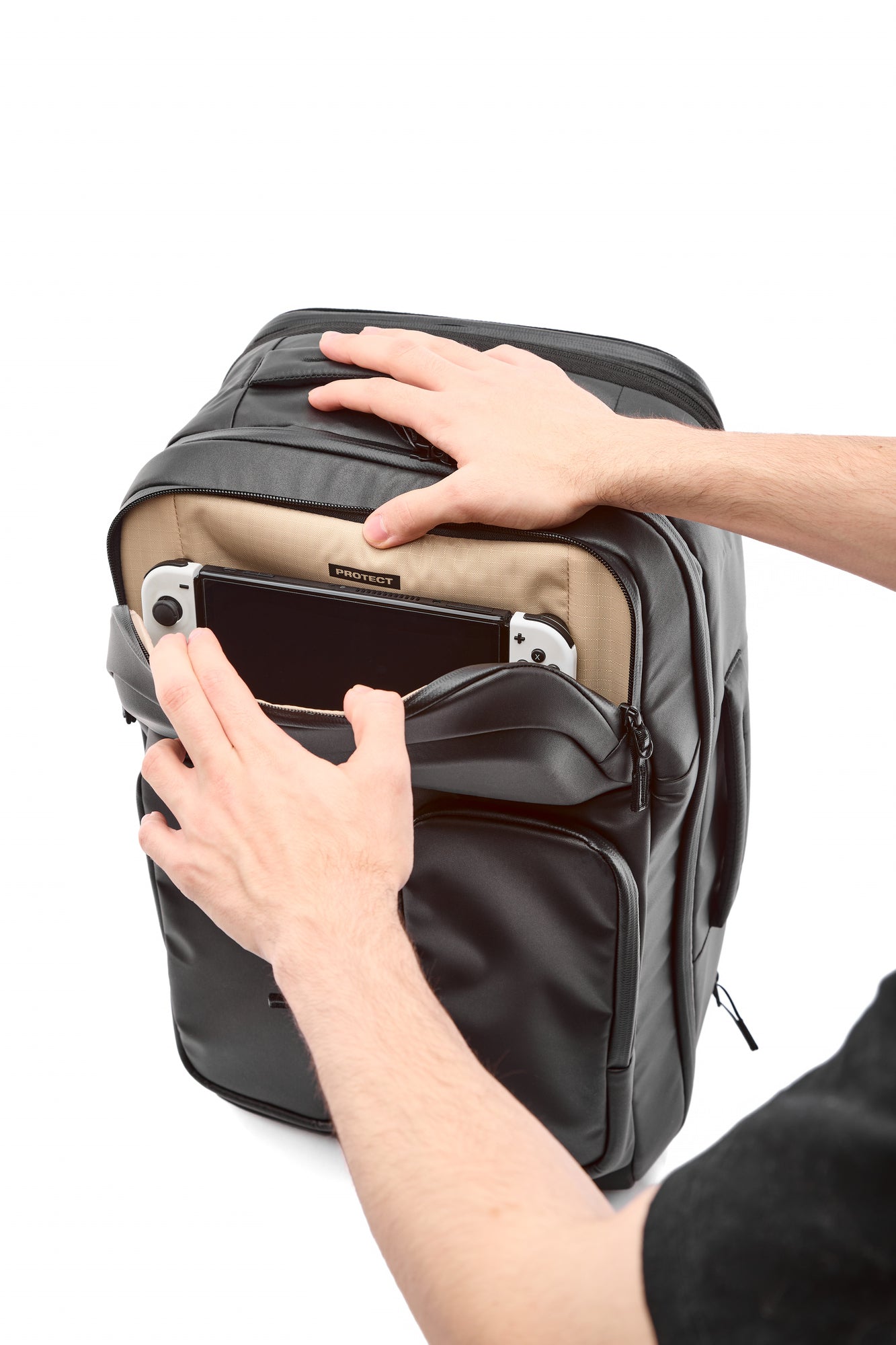 Person opening a black backpack with a white background