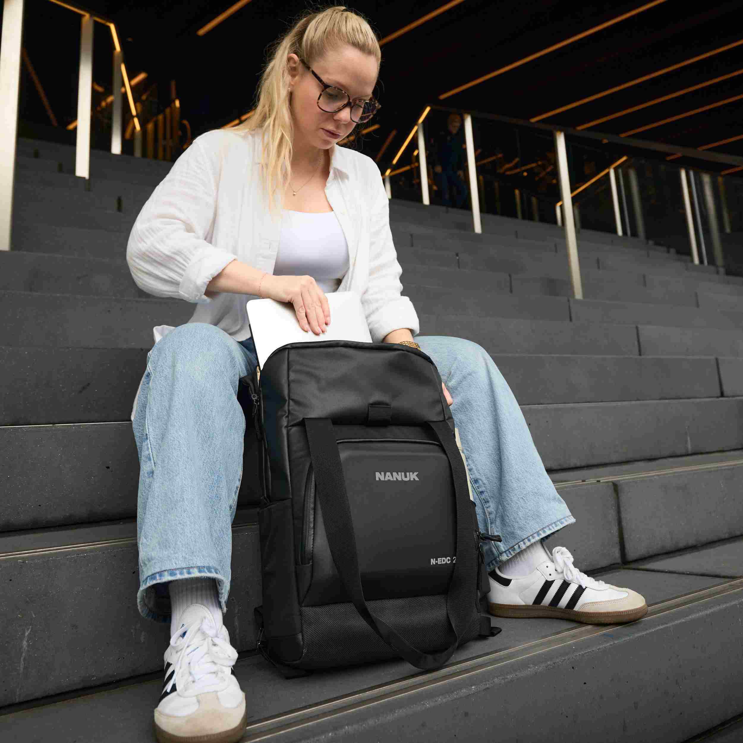 Woman sitting on steps with a black Nanuk backpack