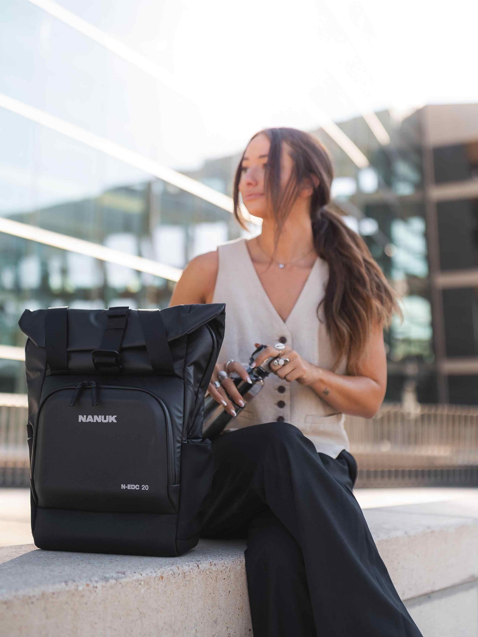 Woman sitting with a black Nanuk backpack in an urban setting