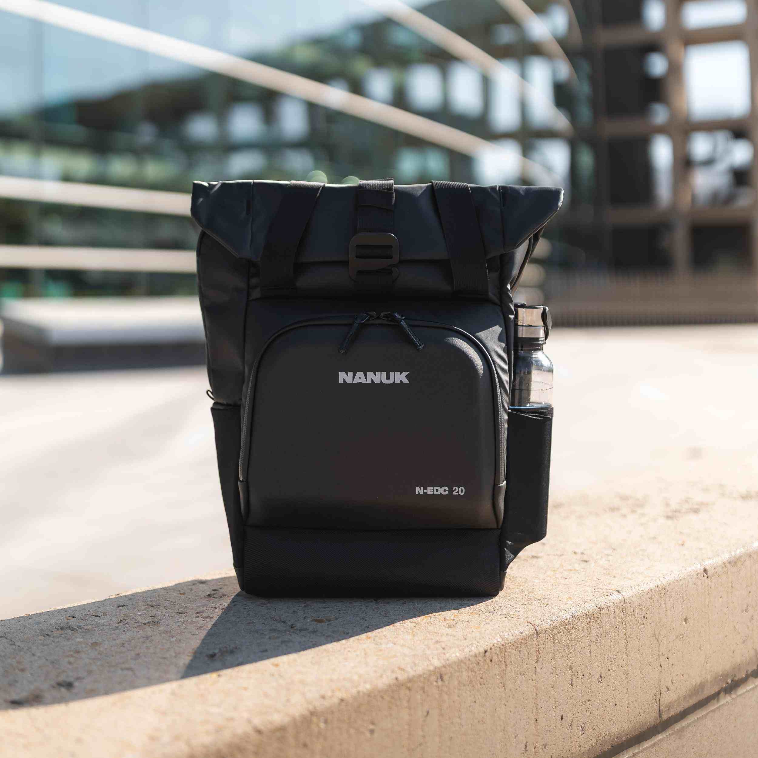 Black Nanuk backpack on a concrete ledge with blurred background