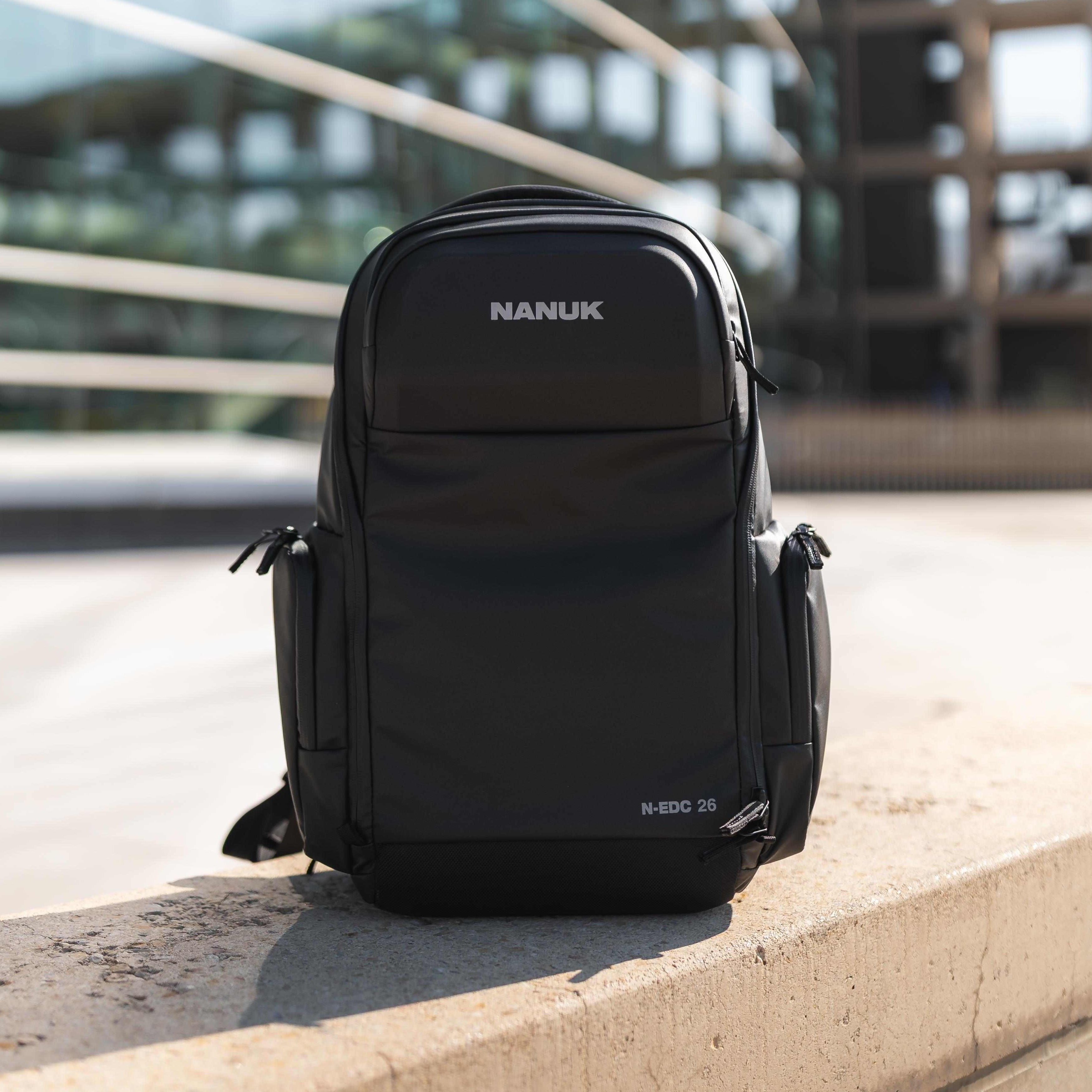 Black Nanuk backpack on a concrete ledge with a blurred background