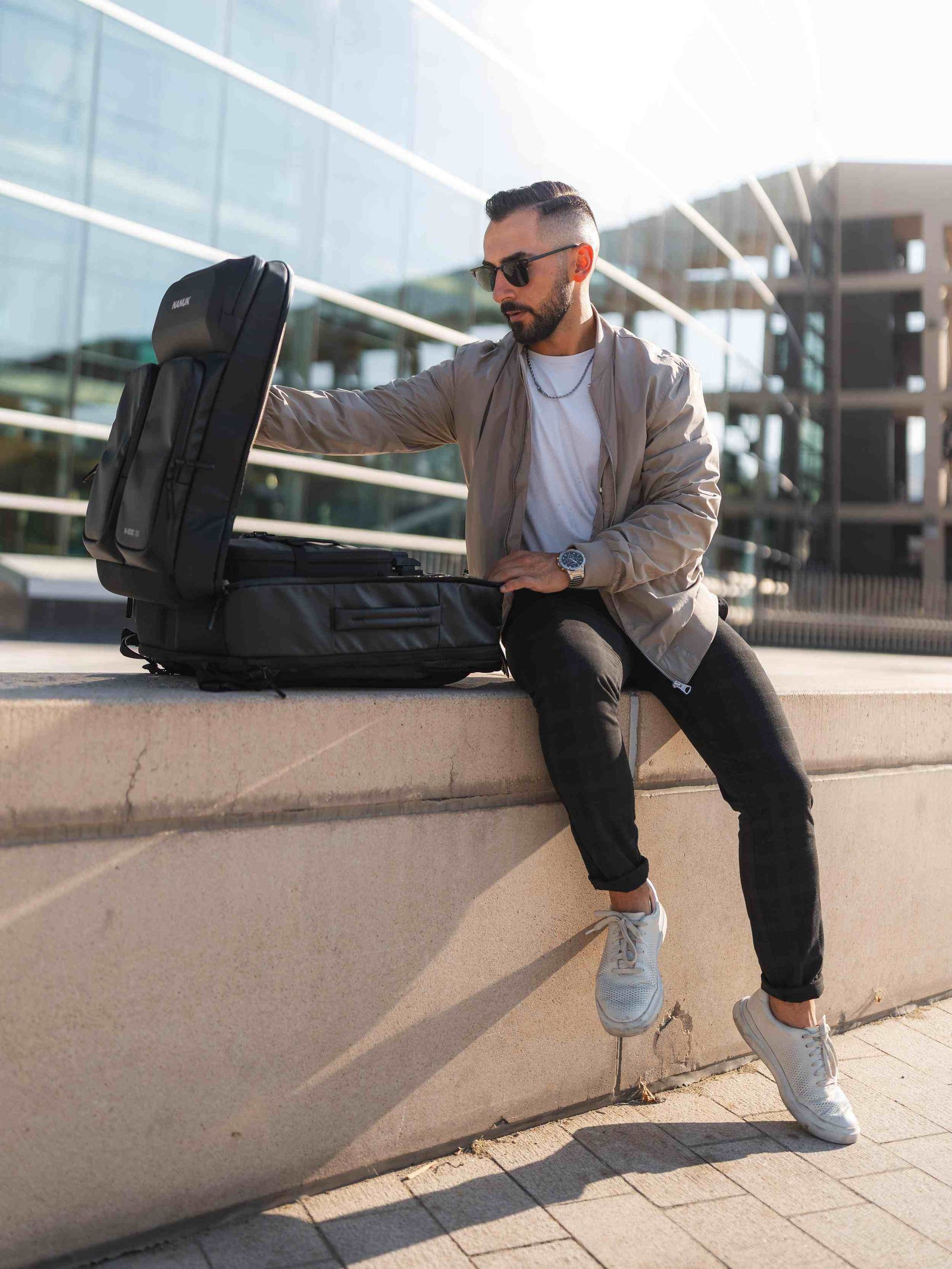 Man sitting on a ledge with a large black backpack in an urban setting