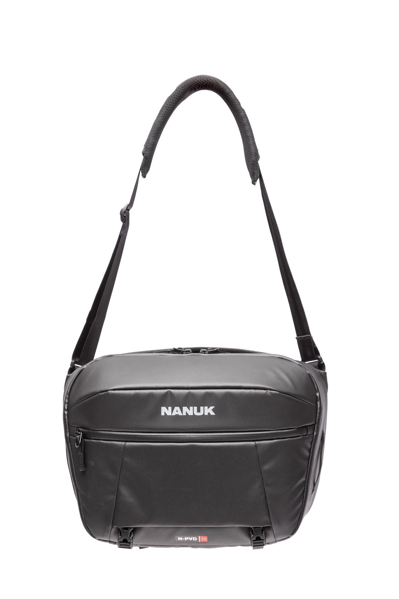 A black Nanuk camera shoulder bag with a front zippered pocket and a white brand logo, shown against a plain white background.