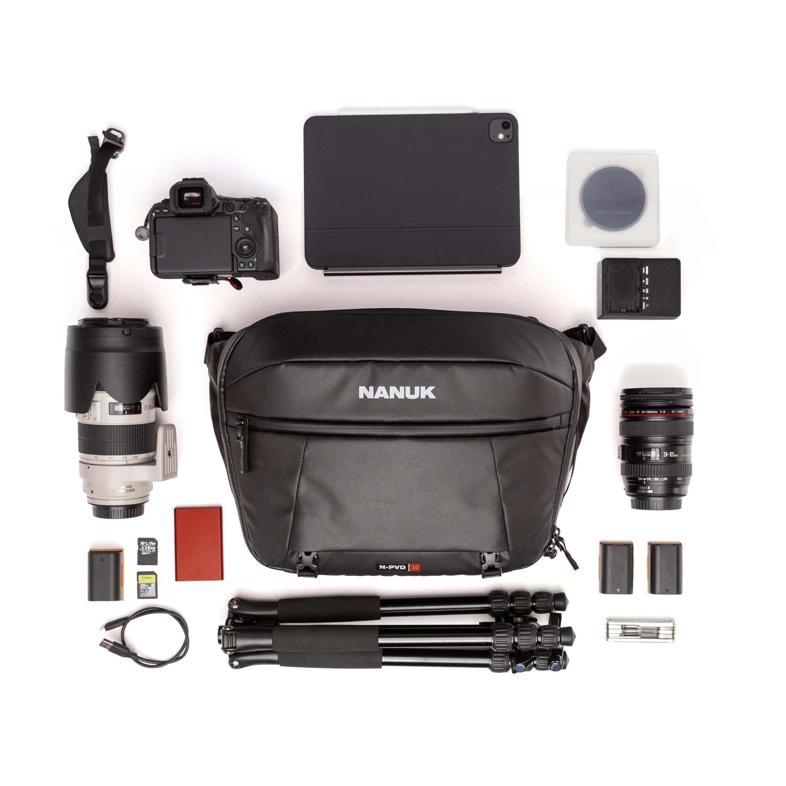 A flat-lay product presentation of a black Nanuk SLR Pro 20 camera bag surrounded by various photography accessories, including a DSLR camera, lenses, tripod, tablet, battery, and cards, on a solid white background.