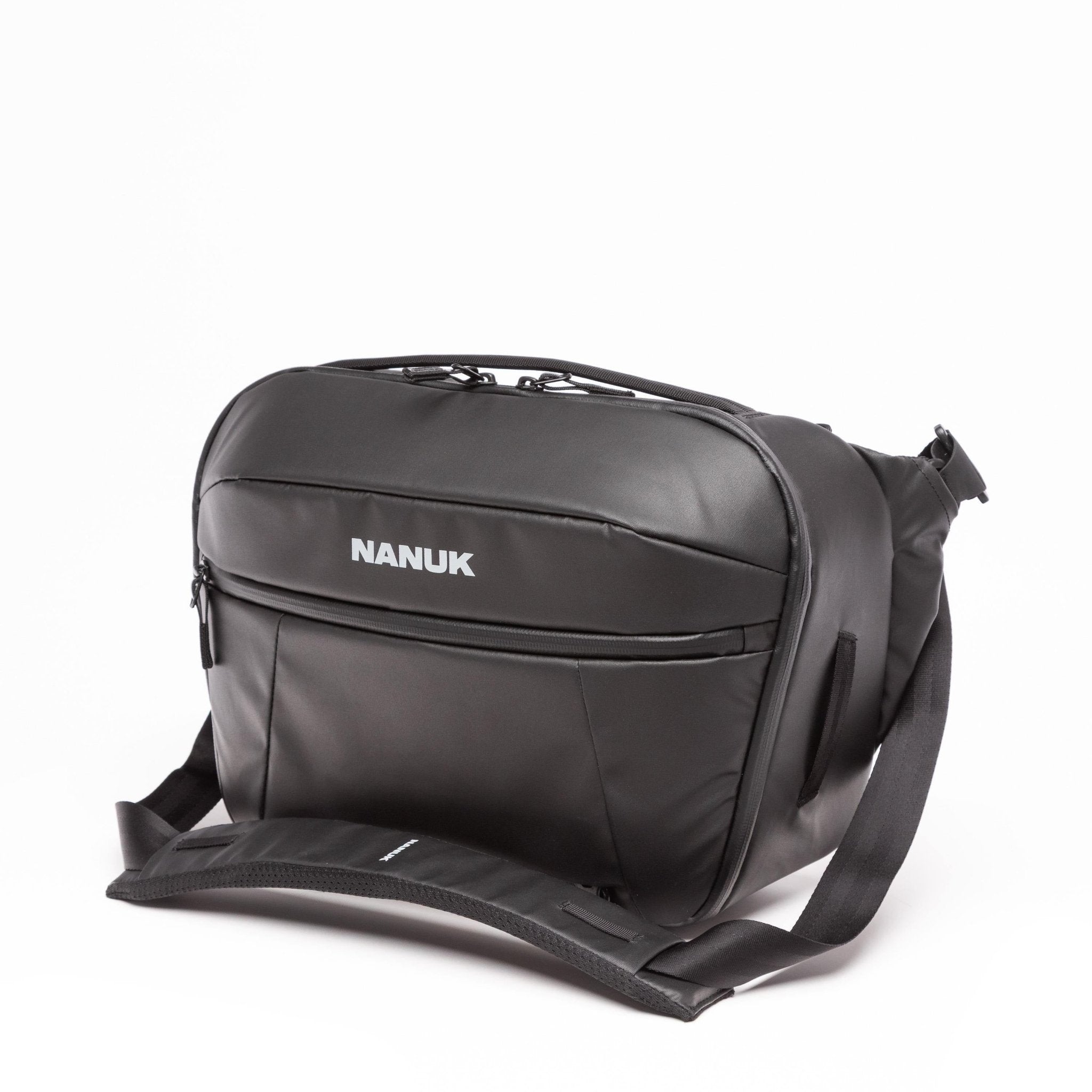 A black Nanuk messenger bag with a white brand logo, shown on a clean white background with its detachable shoulder strap extended.