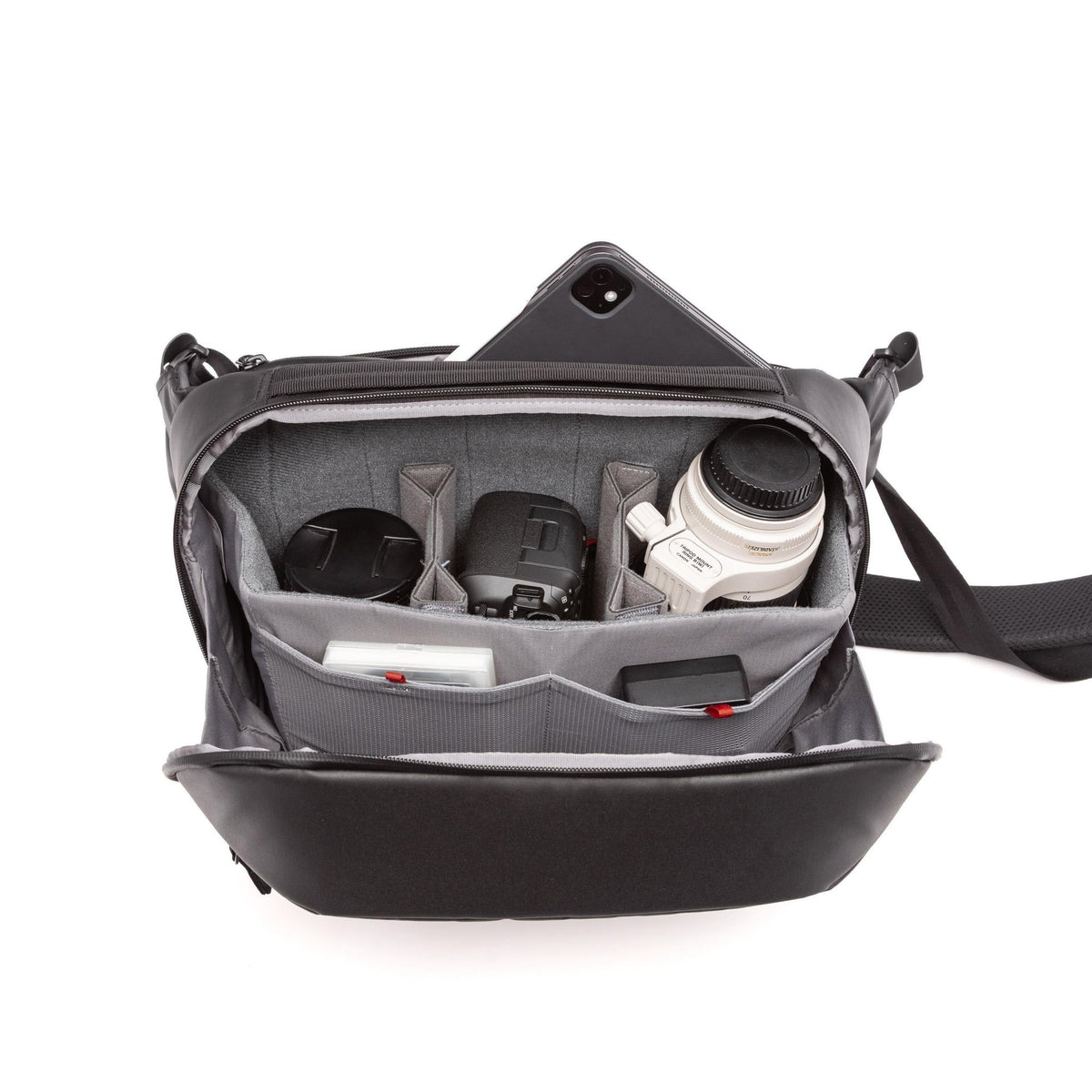 A black and gray camera shoulder bag shown open, filled with camera gear including a lens, camera body, and accessories, on a white background.