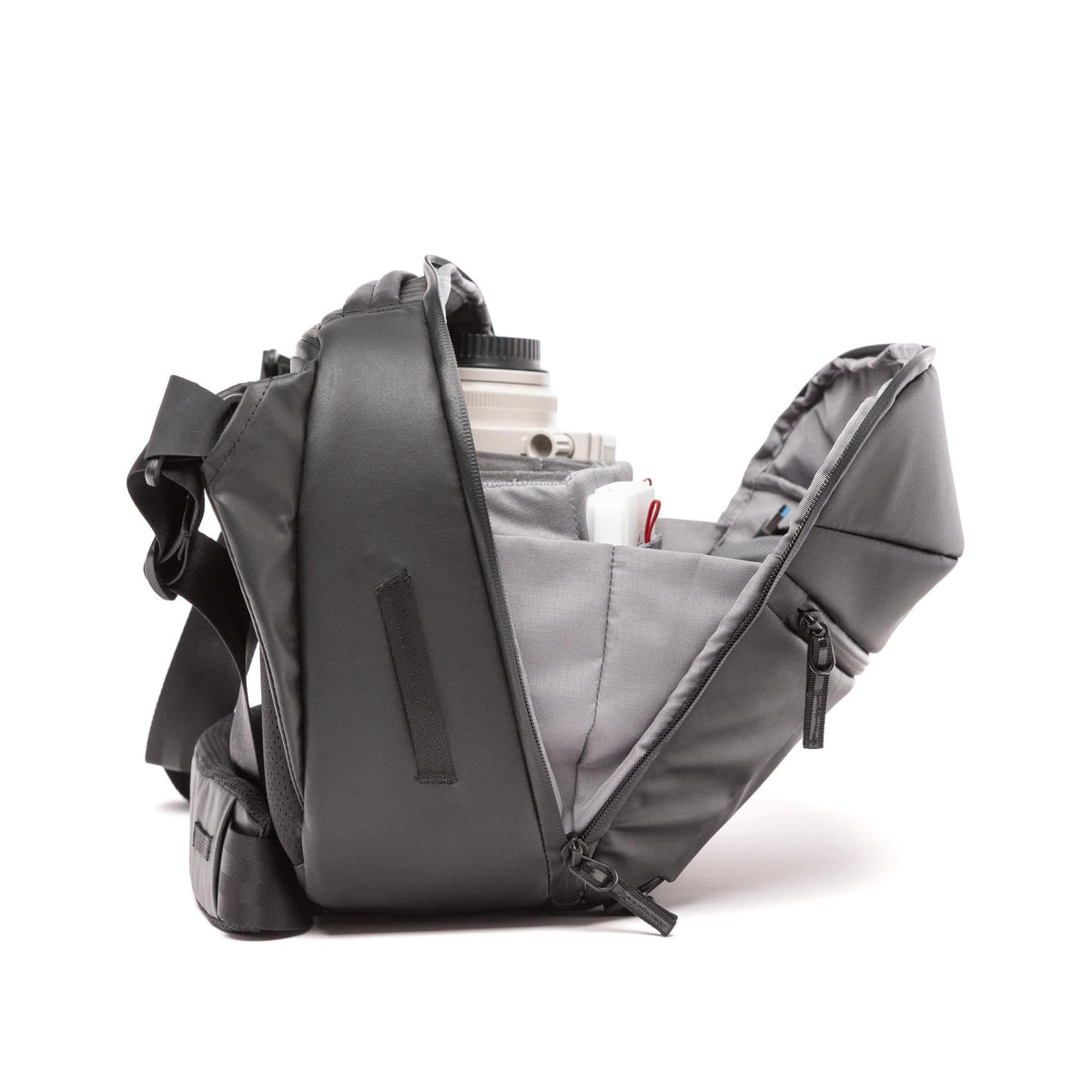 A dark gray camera shoulder bag shown open, displaying its interior compartments and a camera lens inside, set against a plain white background.