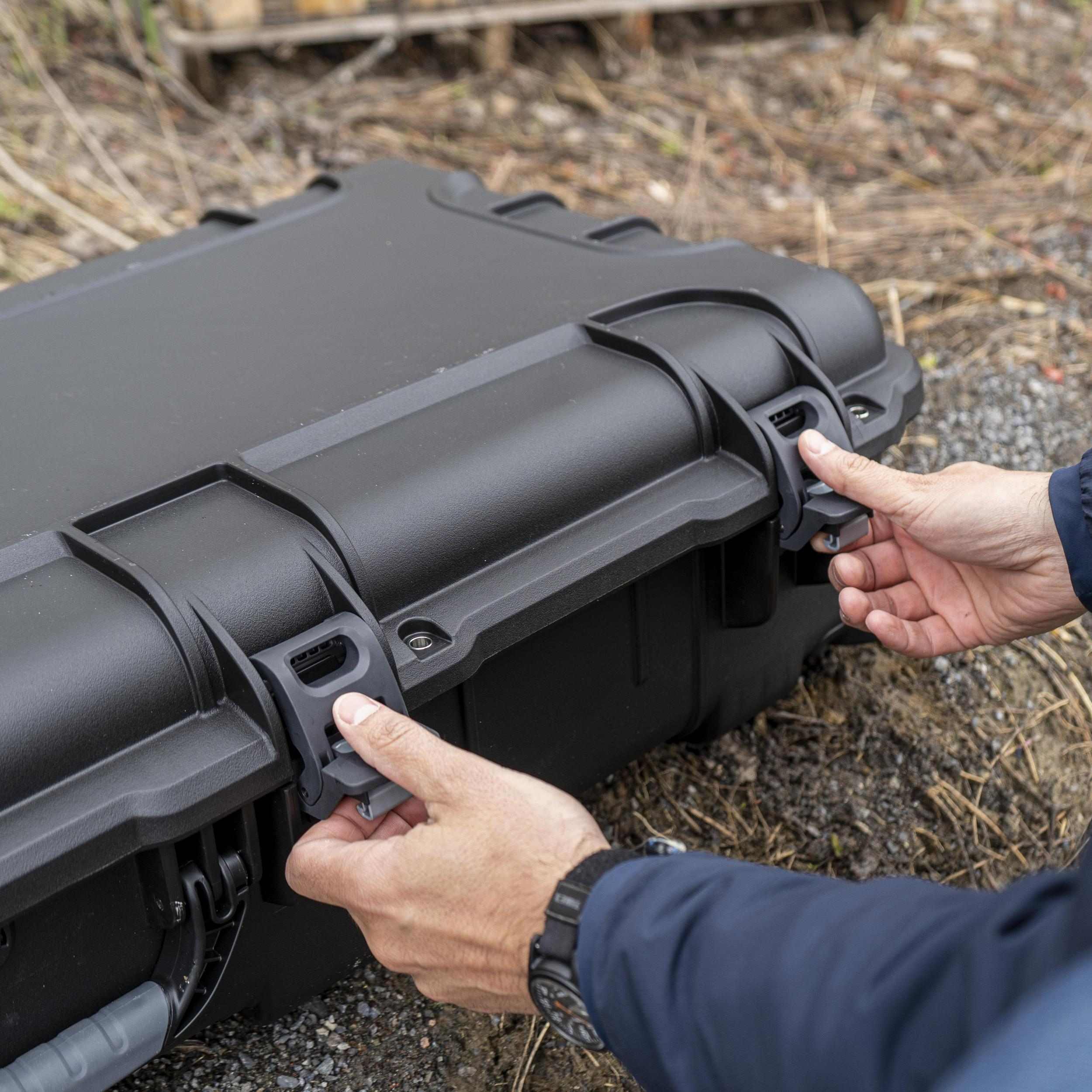 Person opening a black hard-shell case outdoors