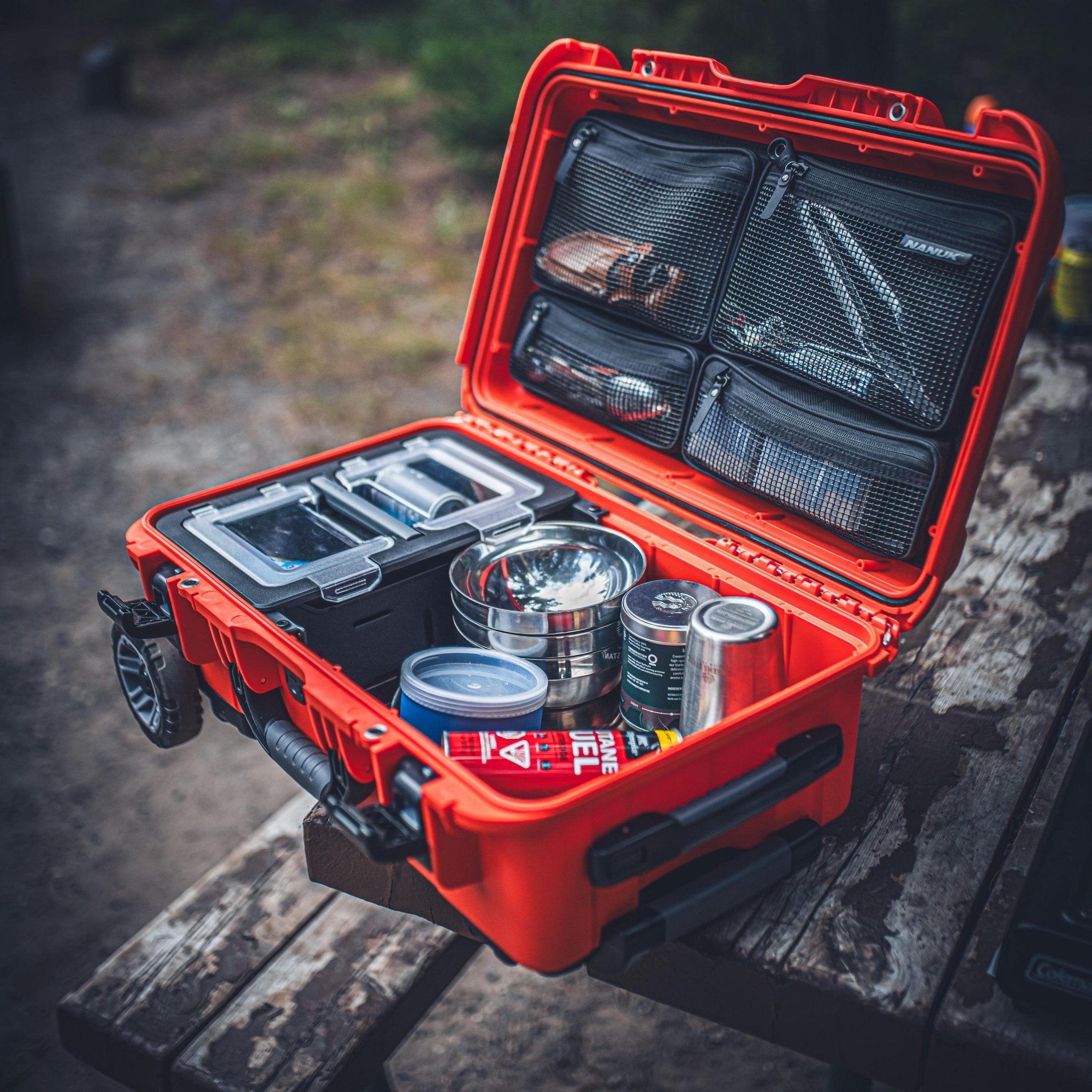 Open red cooler with camping gear on a wooden surface