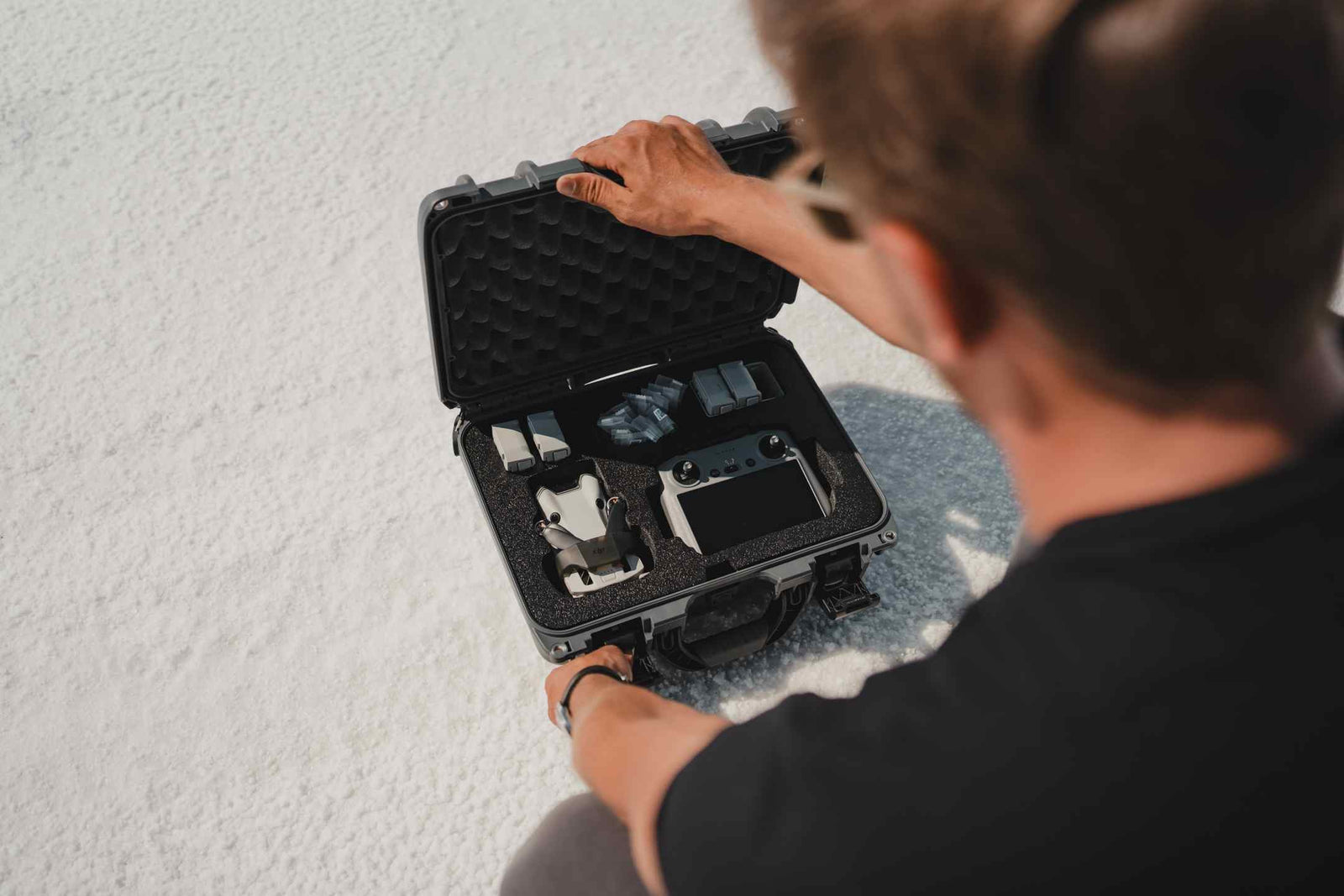 Person opening a black hard-shell case on a light gray background