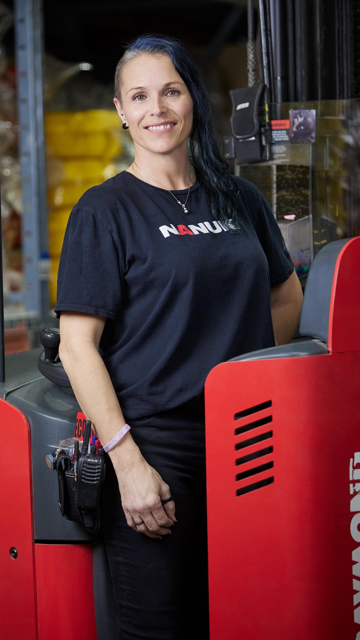 Person wearing a black shirt with 'Nanuk' logo standing next to a red forklift in an industrial setting.