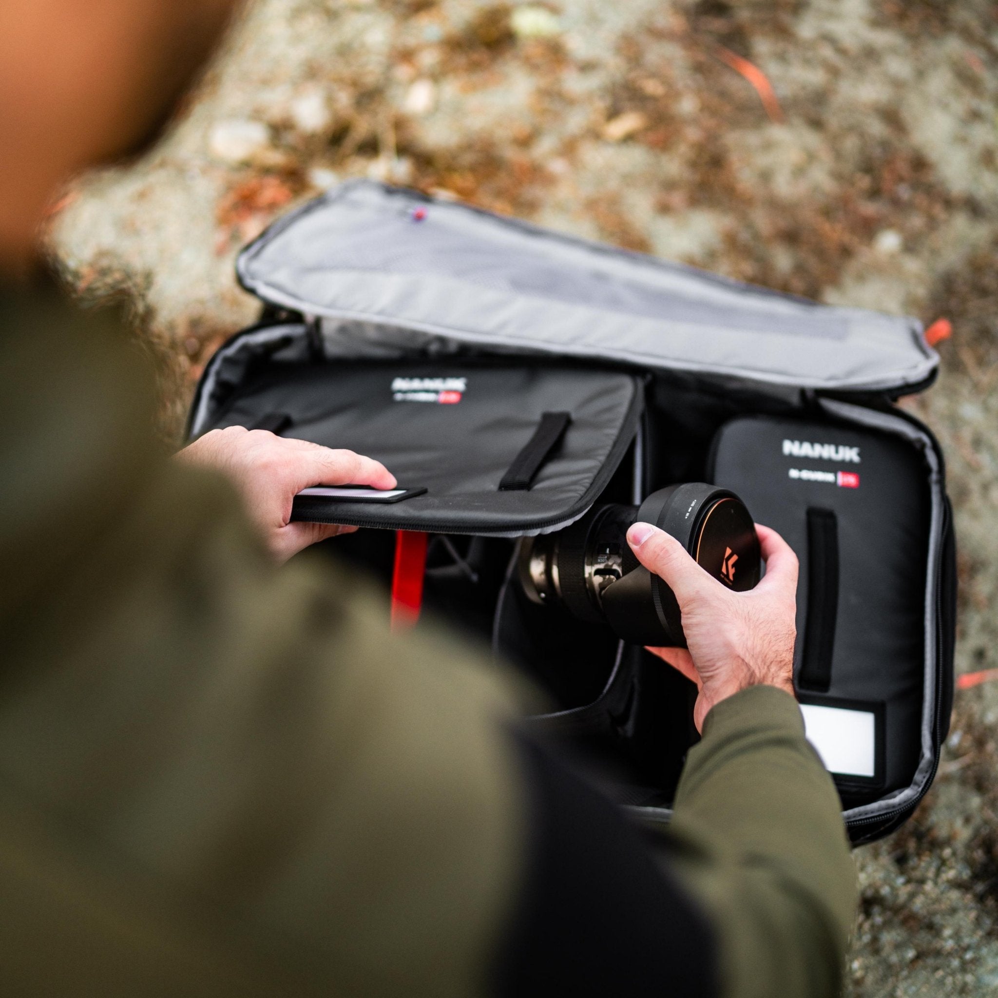 Person opening a black carrying case with equipment on a rocky surface