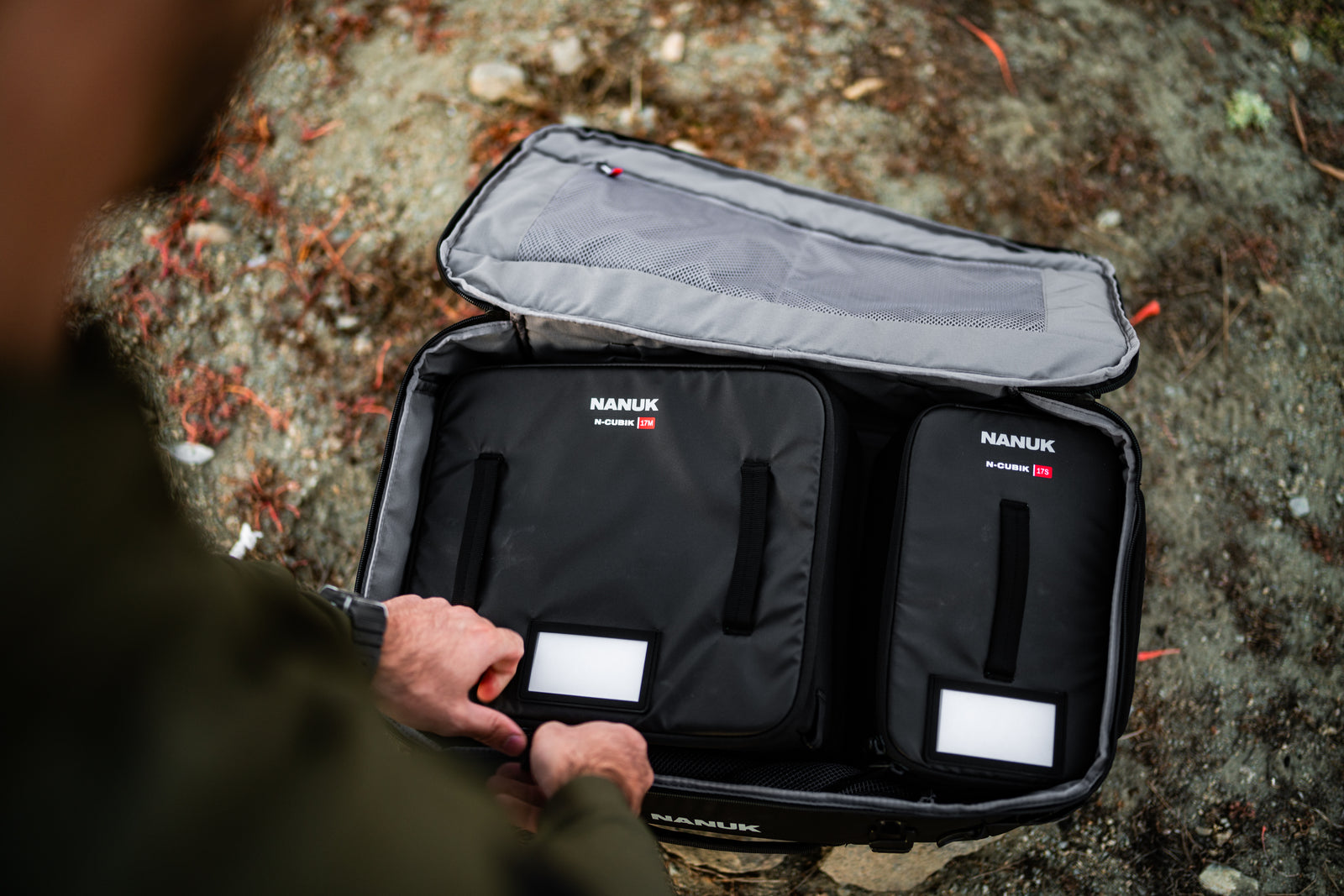 Person holding an open black Nanuk suitcase with visible branding.