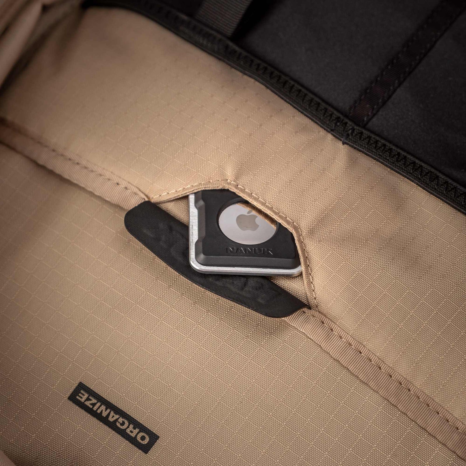 Close-up of a beige bag with a black label and Apple logo, featuring the brand 'Oganize'.
