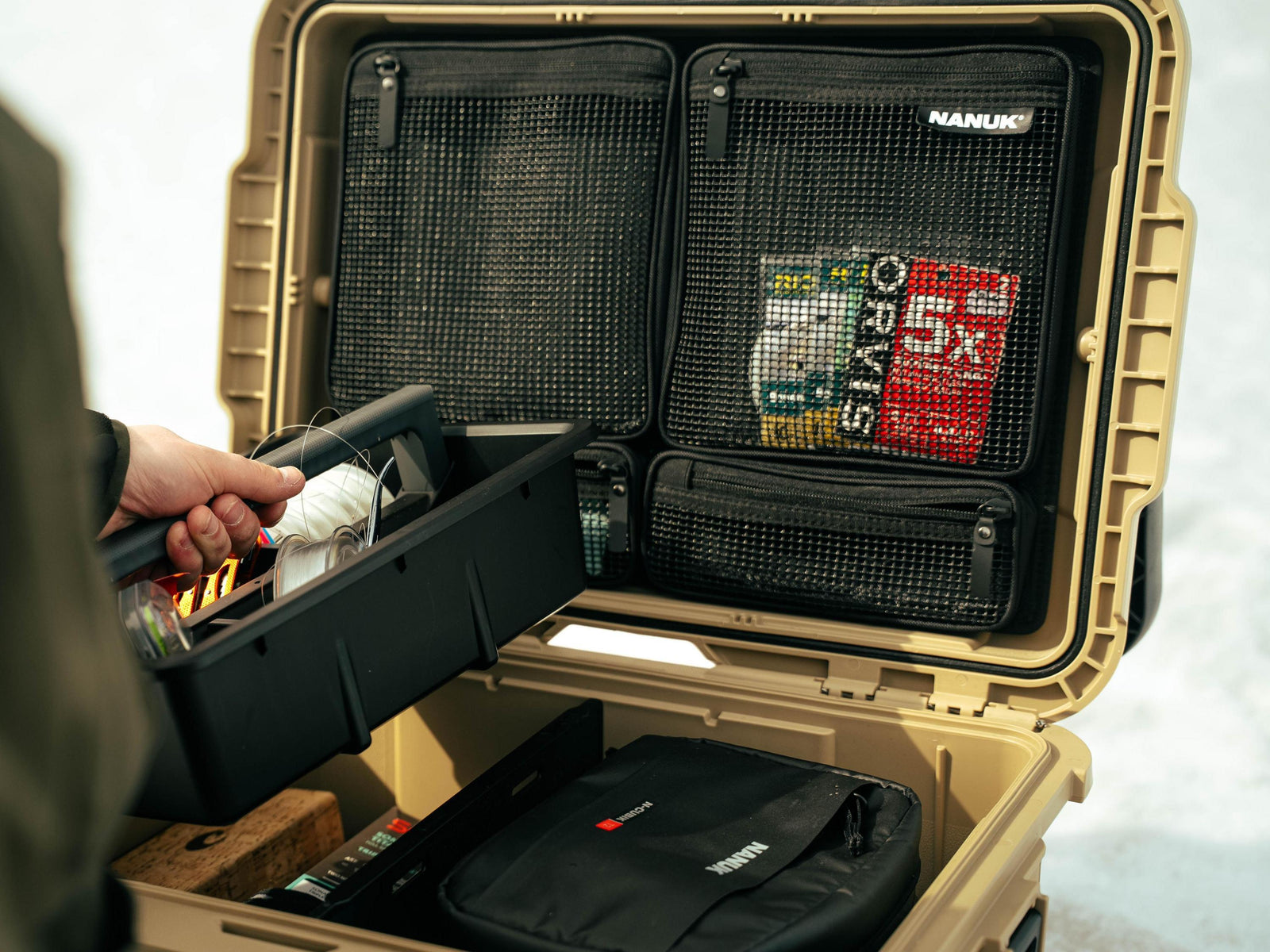 Open beige suitcase with compartments and a visible Nanuk brand label.
