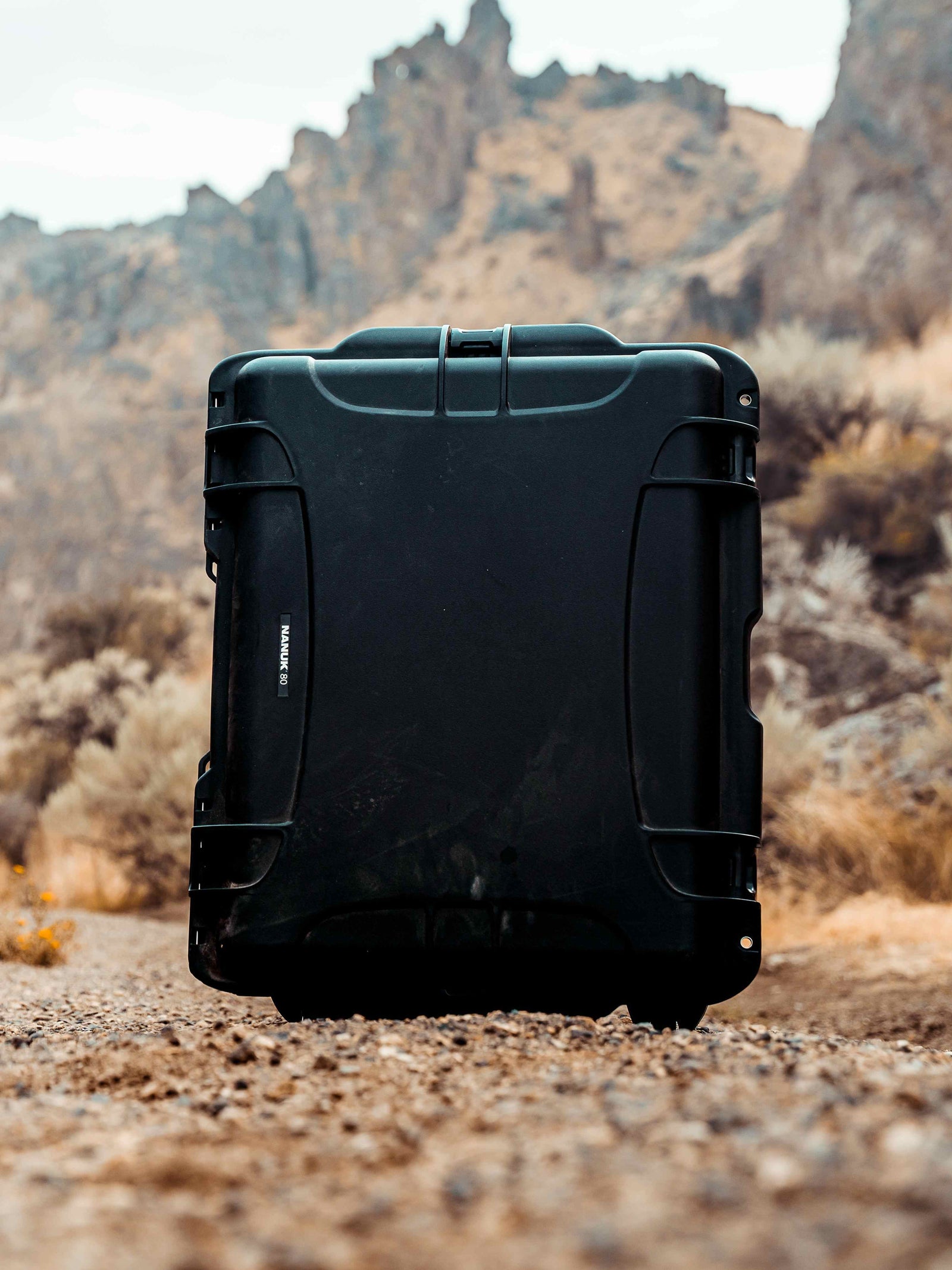 Black suitcase on a rocky terrain with mountains in the background