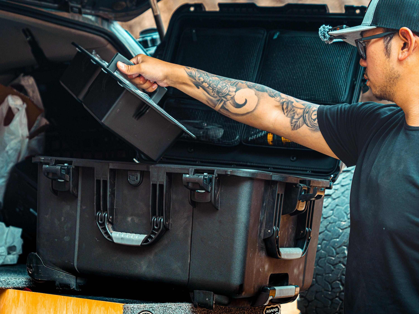 Person opening a large black suitcase in a vehicle