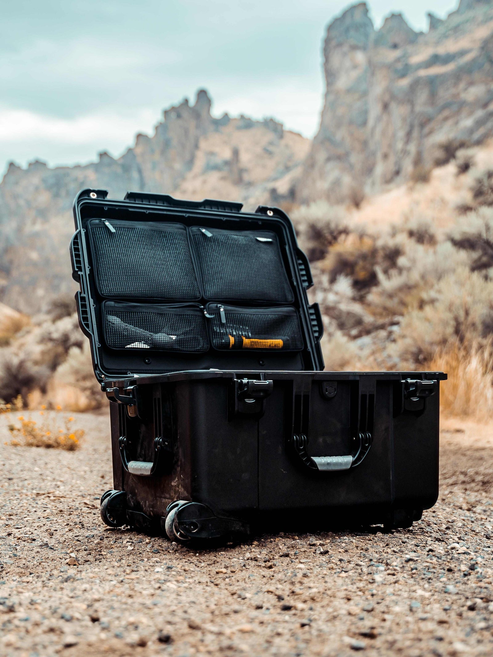 Black open suitcase with contents in a desert landscape