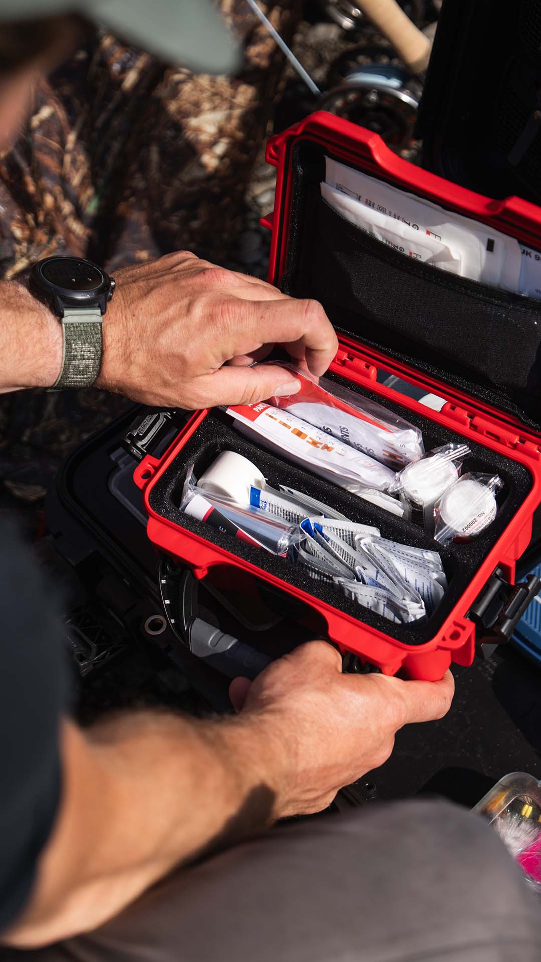 Person opening a red first aid kit with medical supplies.