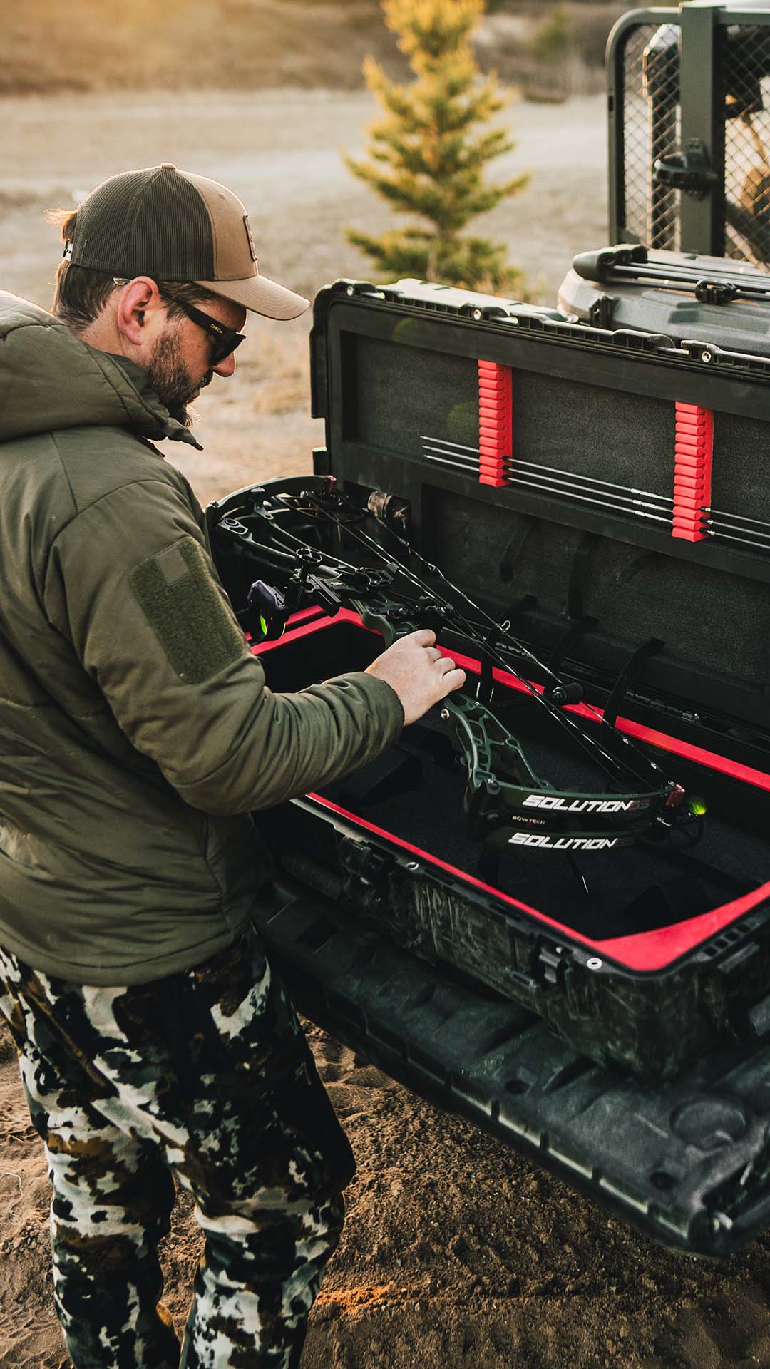 Man organizing hunting gear in a black and red Soltis case outdoors.