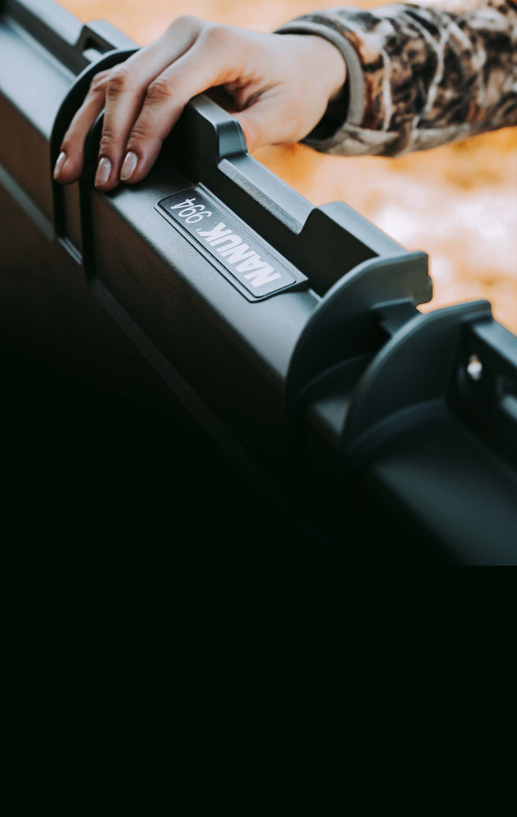 A hand in a camouflage sleeve grips a durable black Nanuk 994 case, perfect for hunting and outdoor promotion.