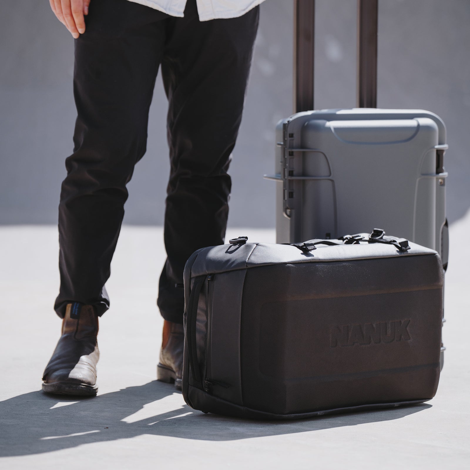 Person standing next to a black suitcase with 'Cleatik' branding on a concrete surface.