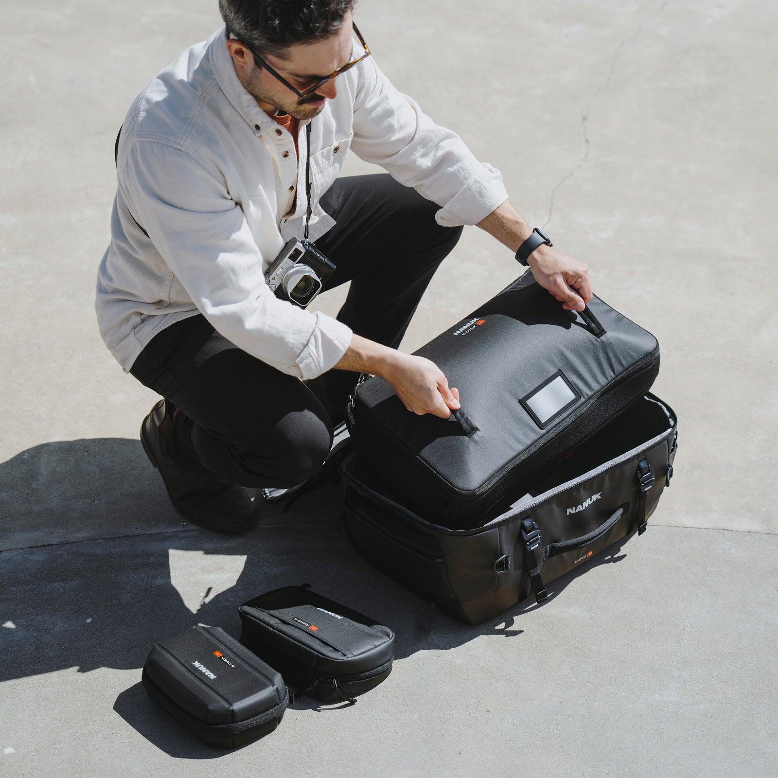 Man opening a black suitcase with a camera on a concrete surface
