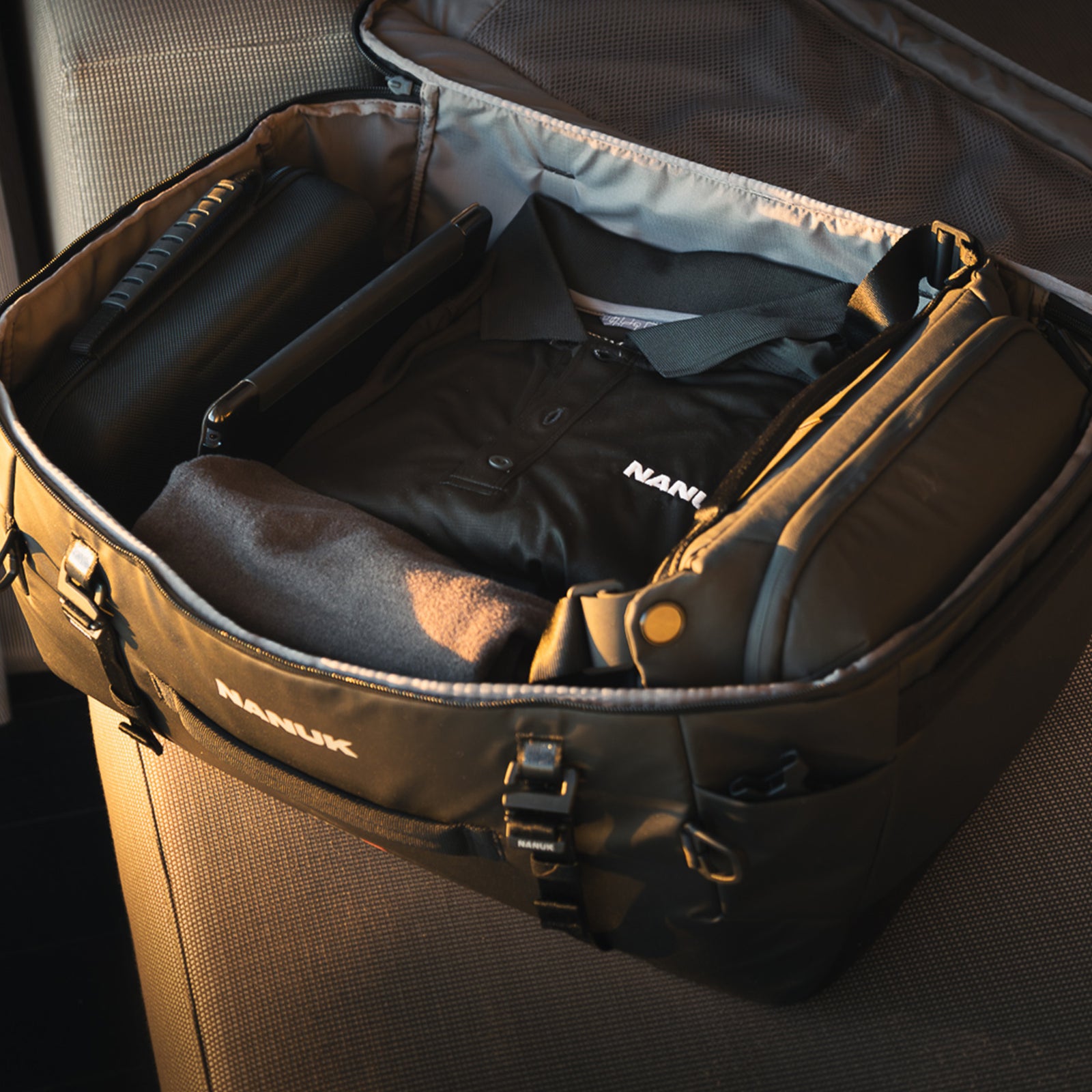 Black jacket with 'Nauk' branding inside an open suitcase.